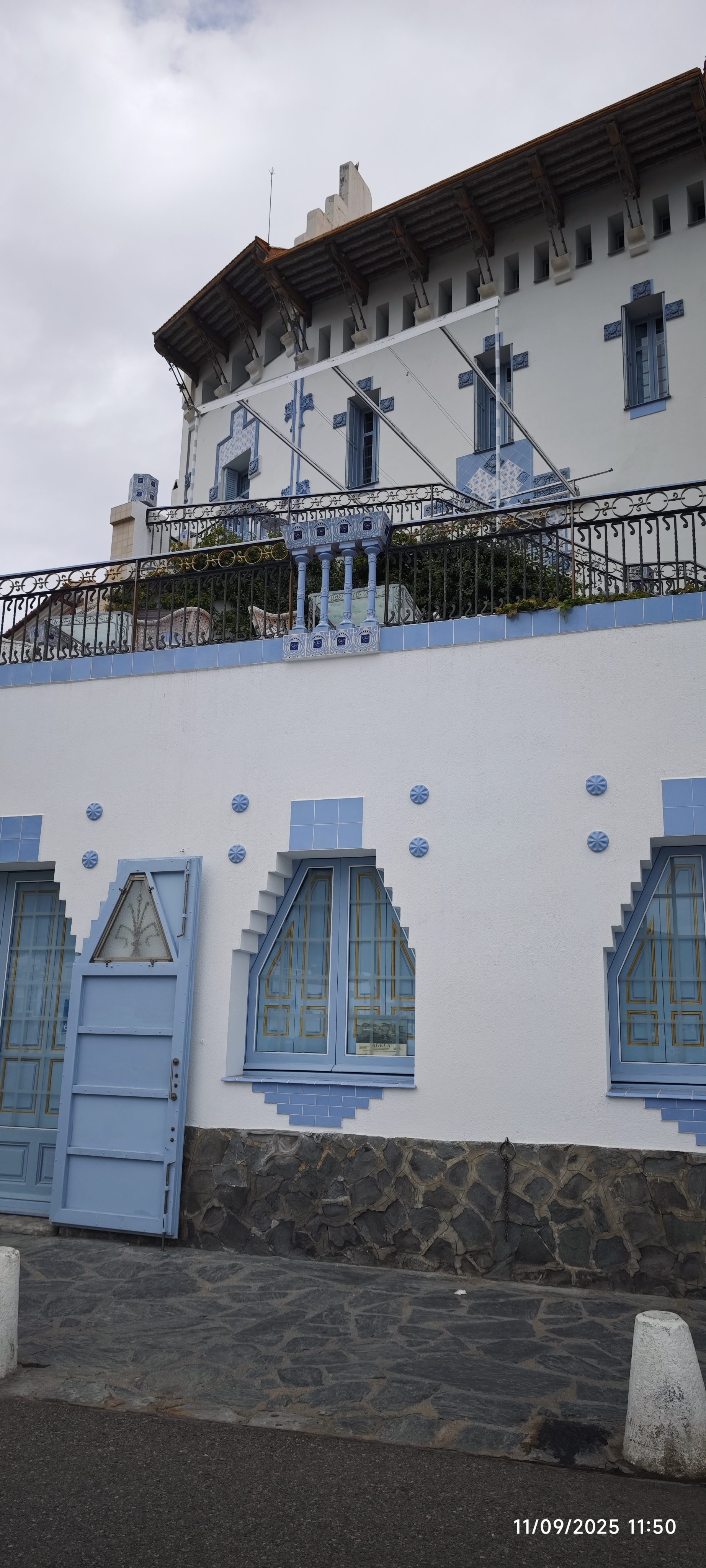 Fachada blanca y azul de estilo modernista con ventanas decoradas en Cadaqués.