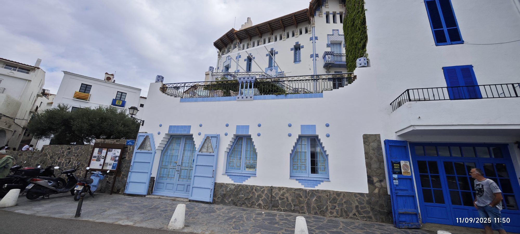 Fachada modernista blanca con marcos de ventanas y azulejos azules en Cadaqués.