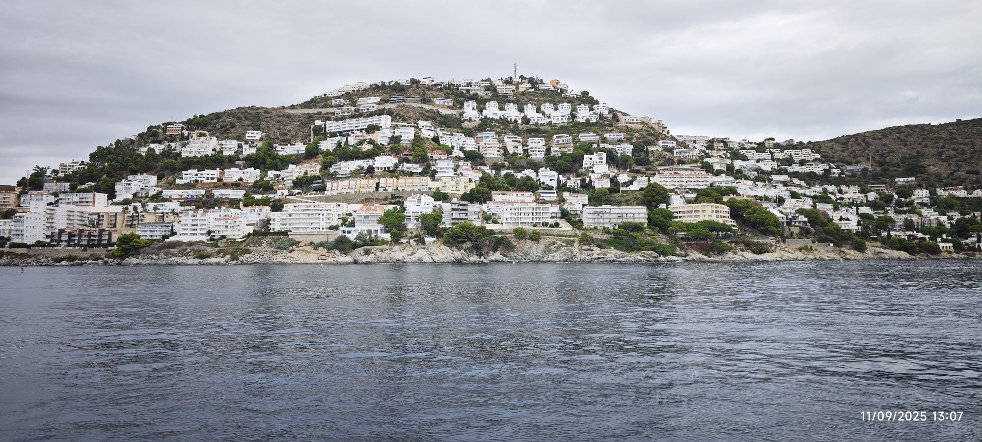 Casas y edificios blancos construidos en una colina costera frente al mar en Roses.