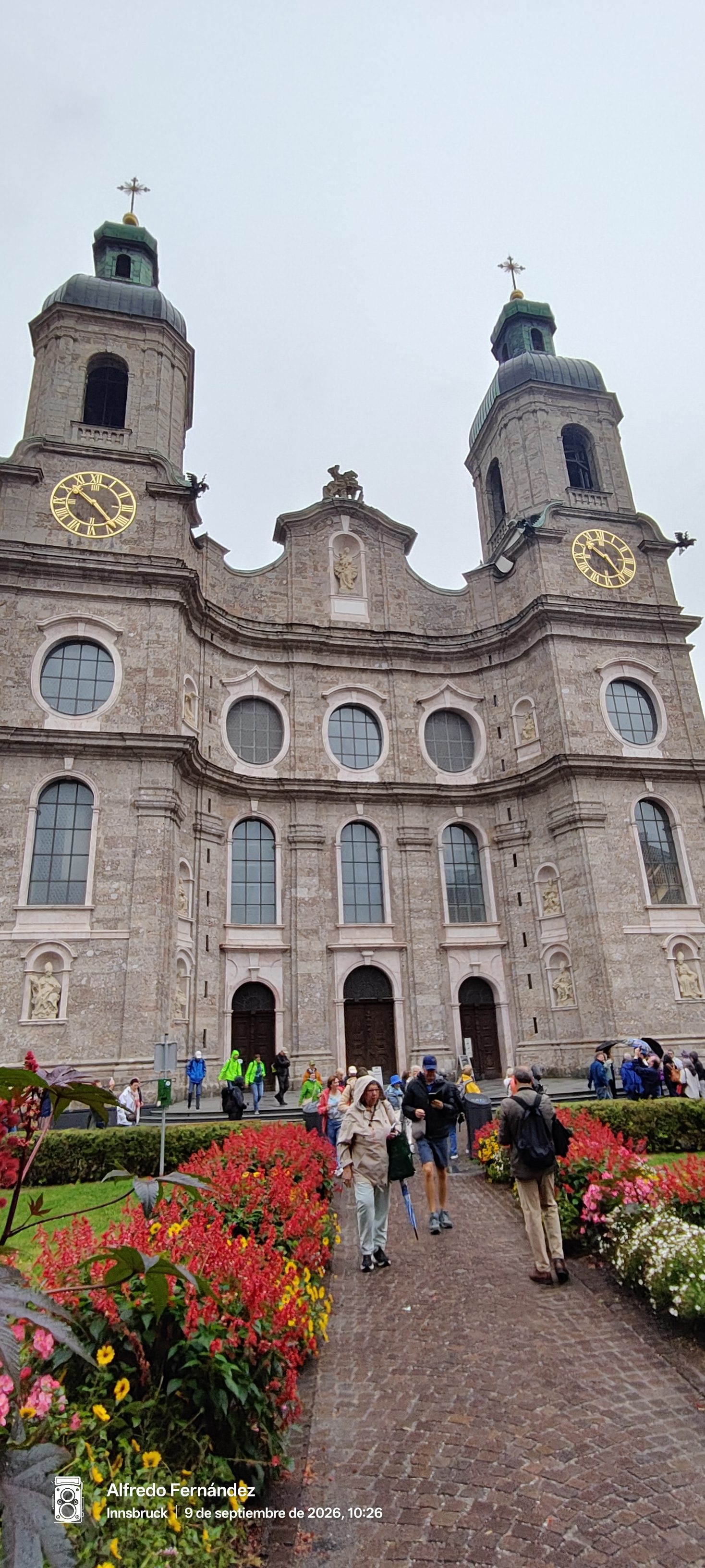 Fachada de piedra de la Catedral de Santiago de Innsbruck entre jardines floridos.