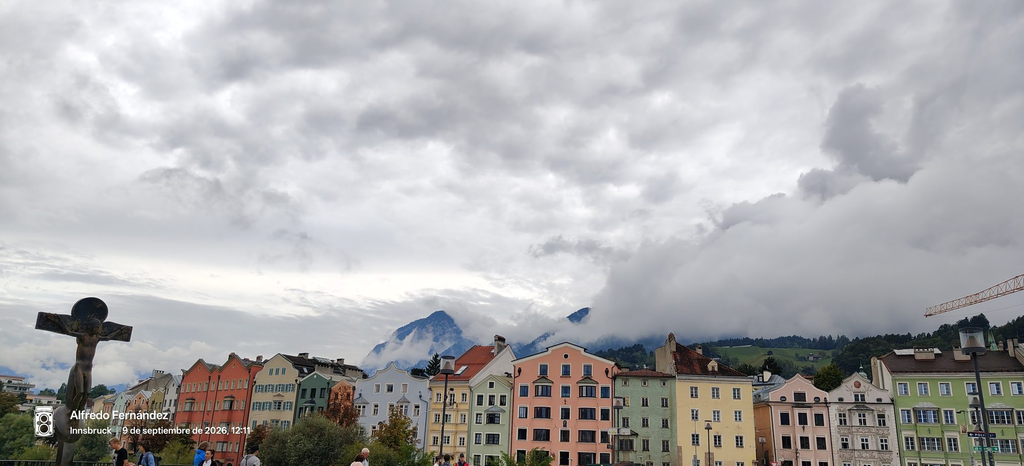 Fachadas de casas de colores en Innsbruck con montañas envueltas en nubes al fondo.
