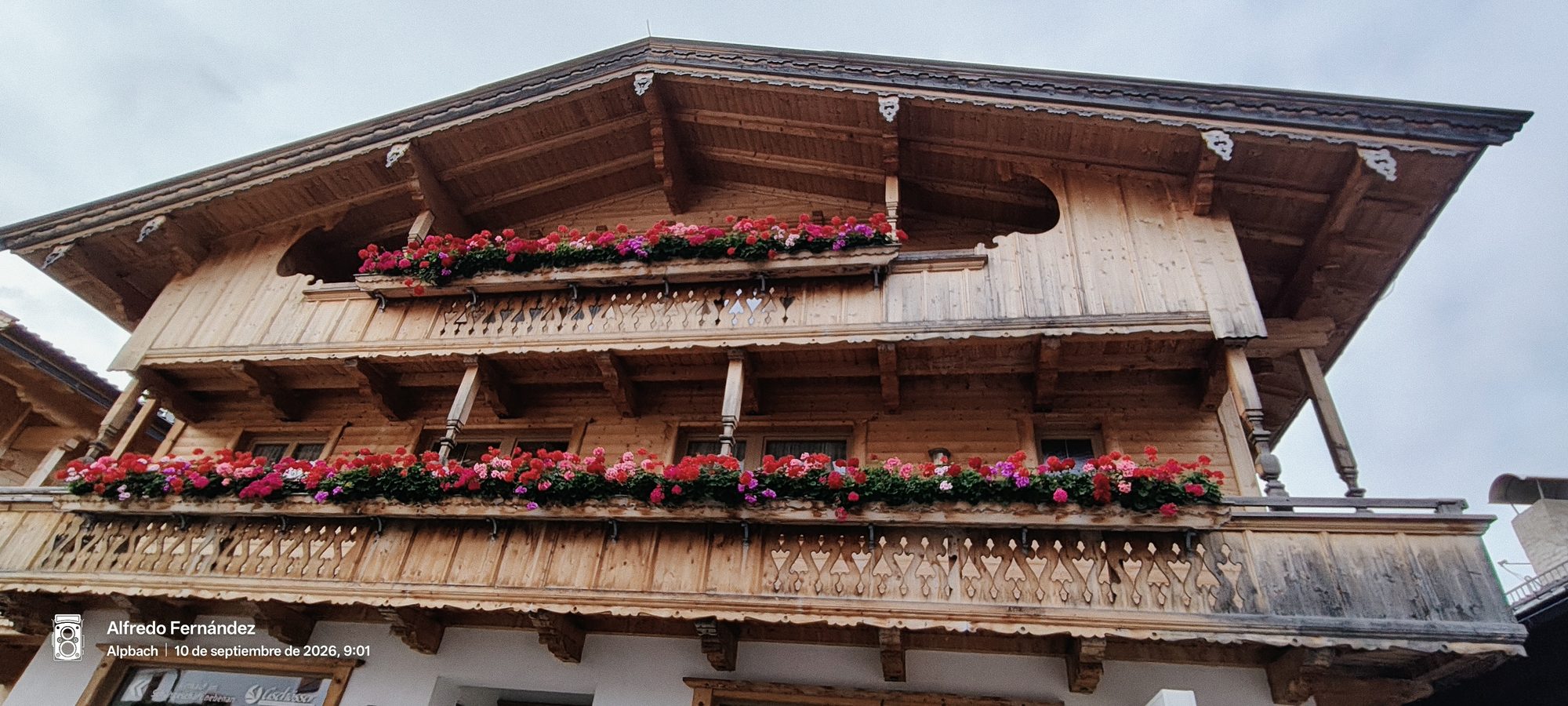 Balcones de madera tradicionales con jardineras de flores rojas en un chalet alpino.