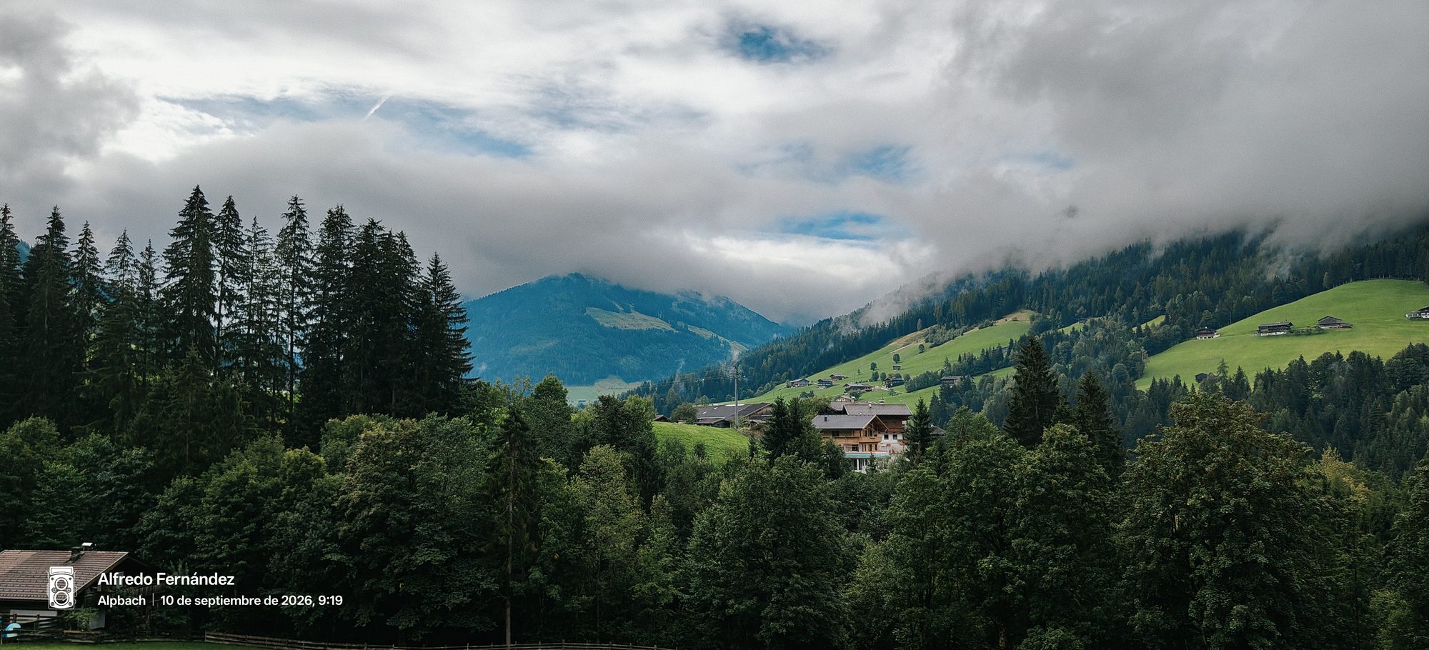 Laderas alpinas boscosas y casas tradicionales bajo nubes bajas en las montañas de Alpbach.