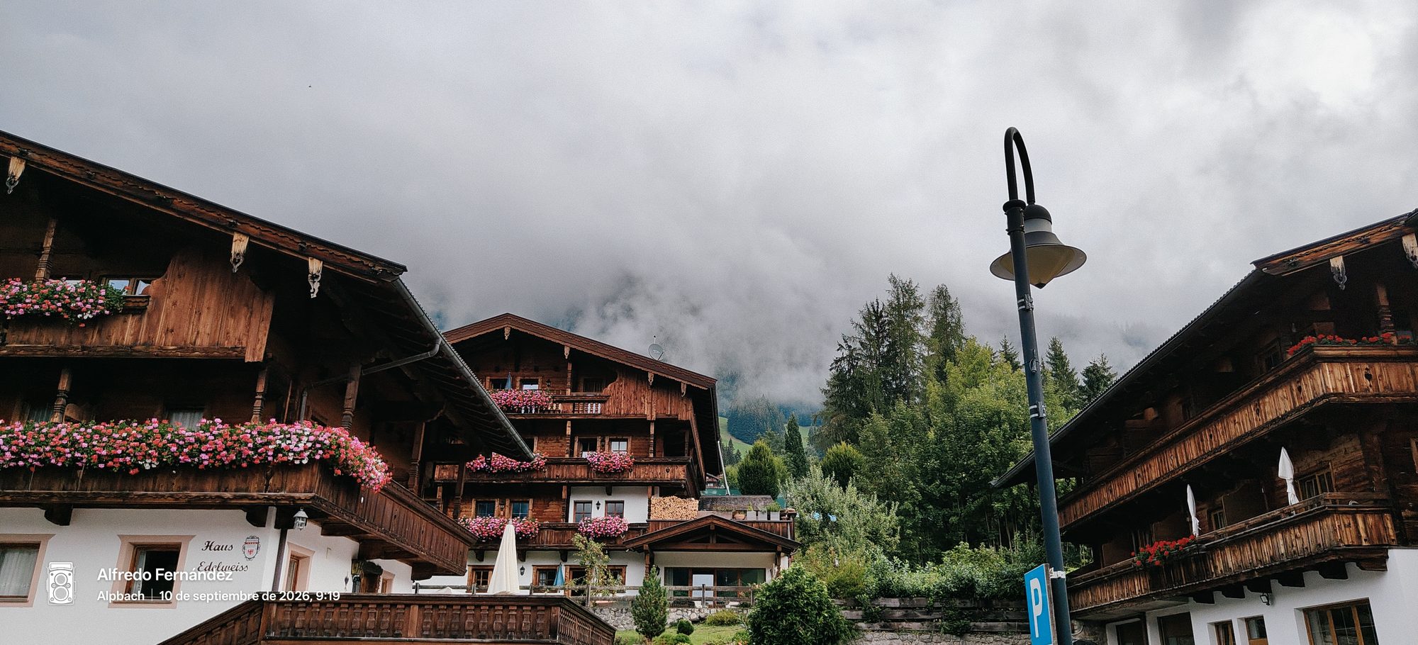 Casas alpinas tradicionales de madera con flores en los balcones bajo la niebla.