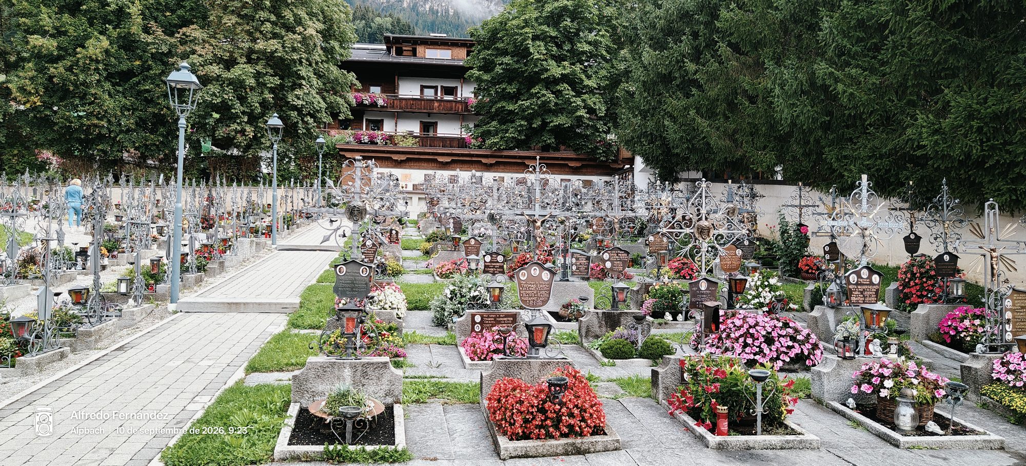 Cementerio tirolés con cruces de hierro forjado adornadas de flores en Alpbach.