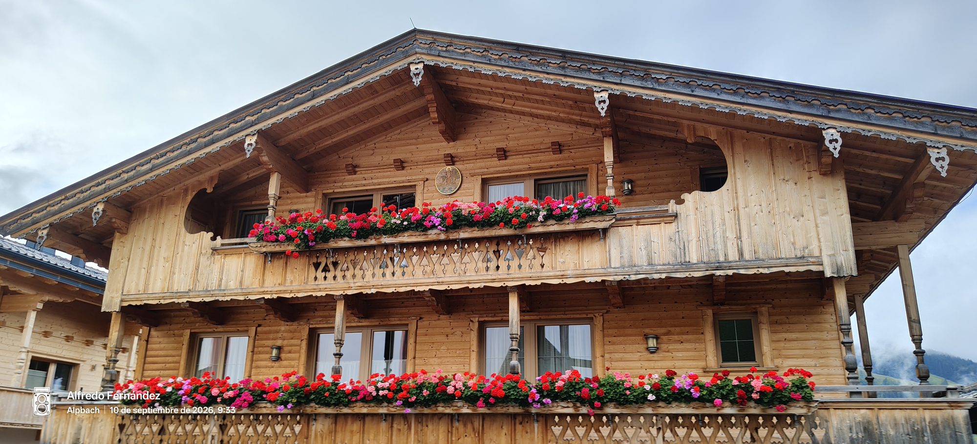 Casa tradicional de madera con balcones decorados con flores rojas en Alpbach
