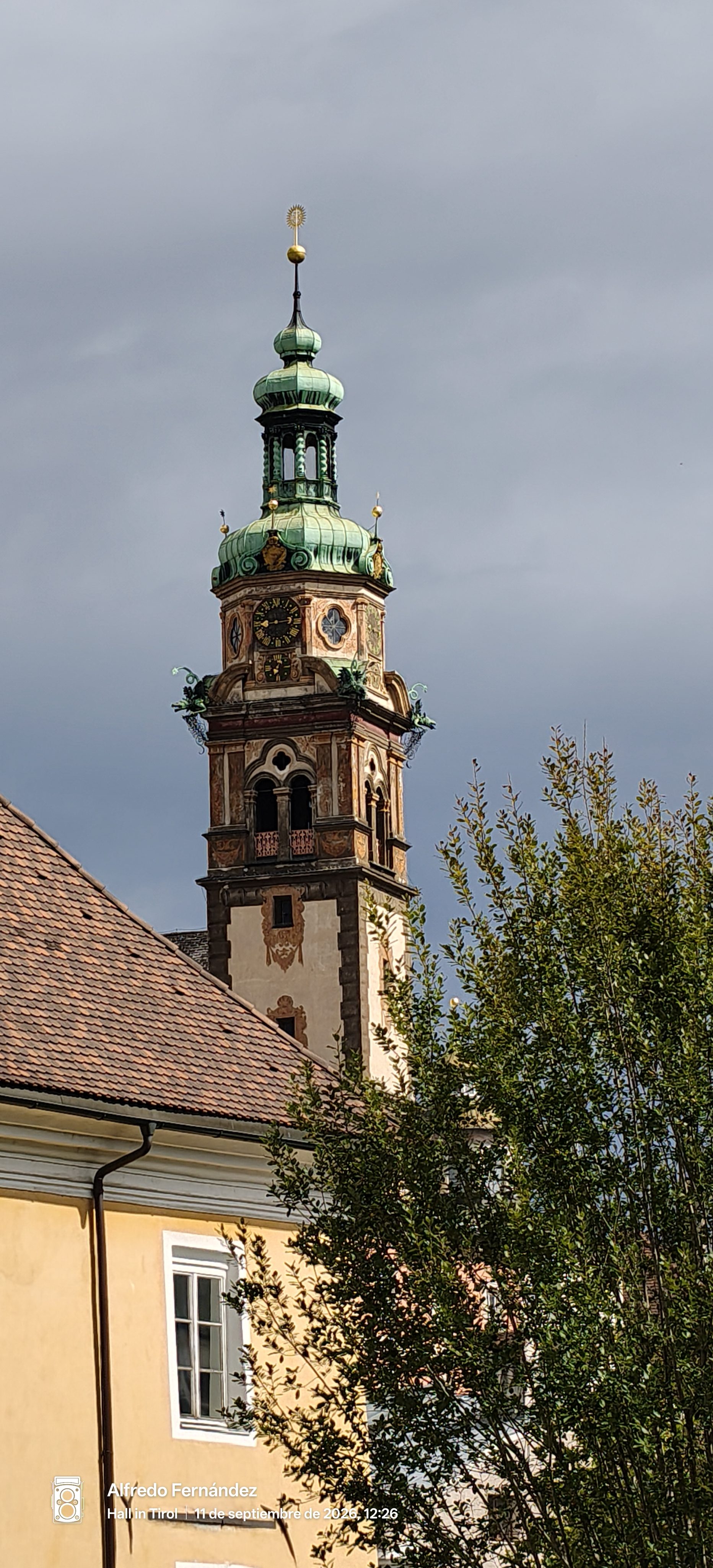 Campanario barroco con cúpula de cobre verde sobre tejados en Hall in Tirol.
