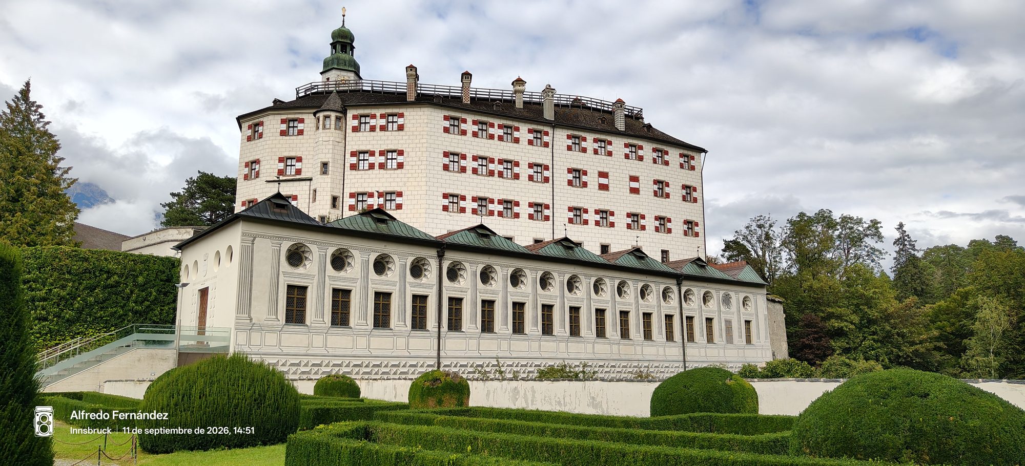 Castillo de Ambras con contraventanas rojas y blancas tras jardines formales en Innsbruck.