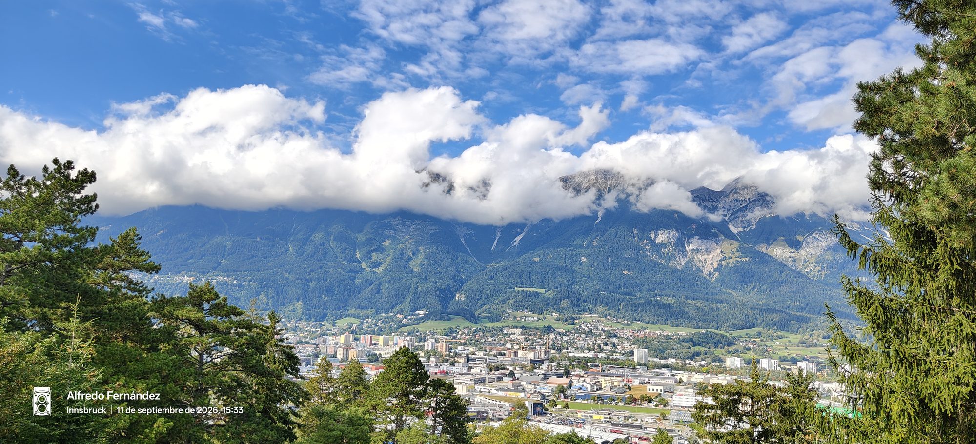 Vista panorámica de Innsbruck rodeada por imponentes montañas alpinas y nubes bajas.