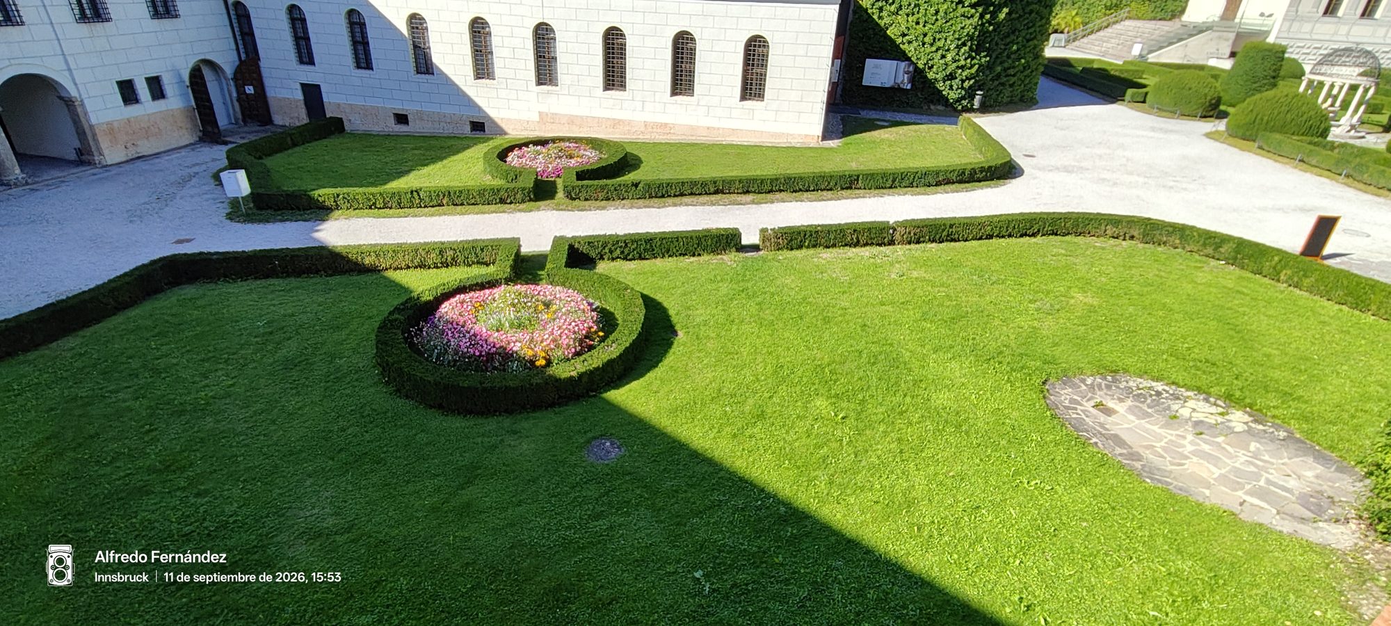 Jardines cuidados con parterres de flores y setos junto a un edificio histórico.