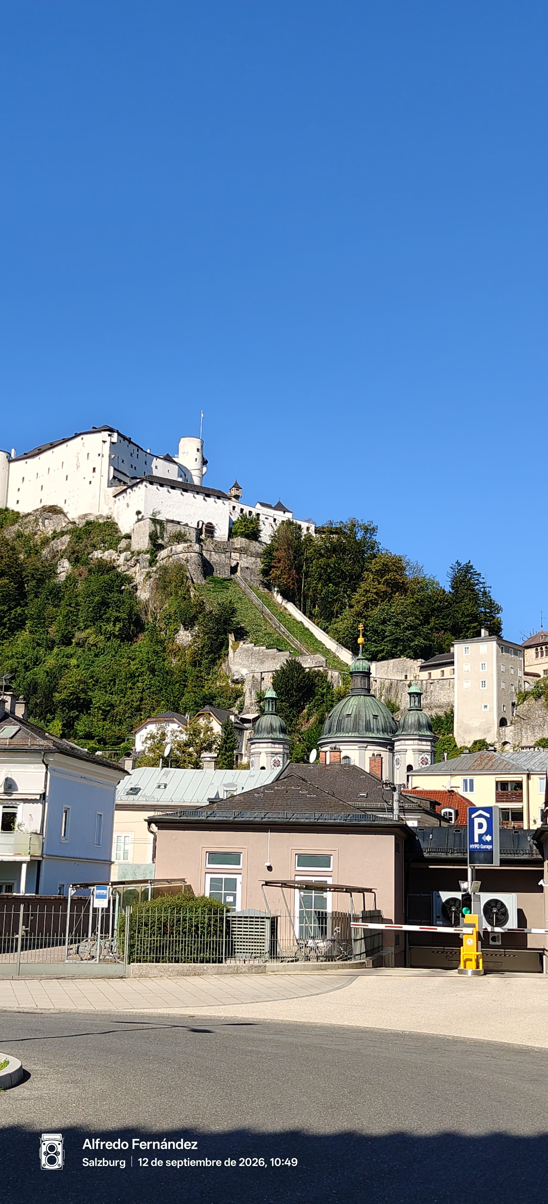 Fortaleza de Hohensalzburg sobre una colina verde con tejados y cúpulas en Salzburgo.