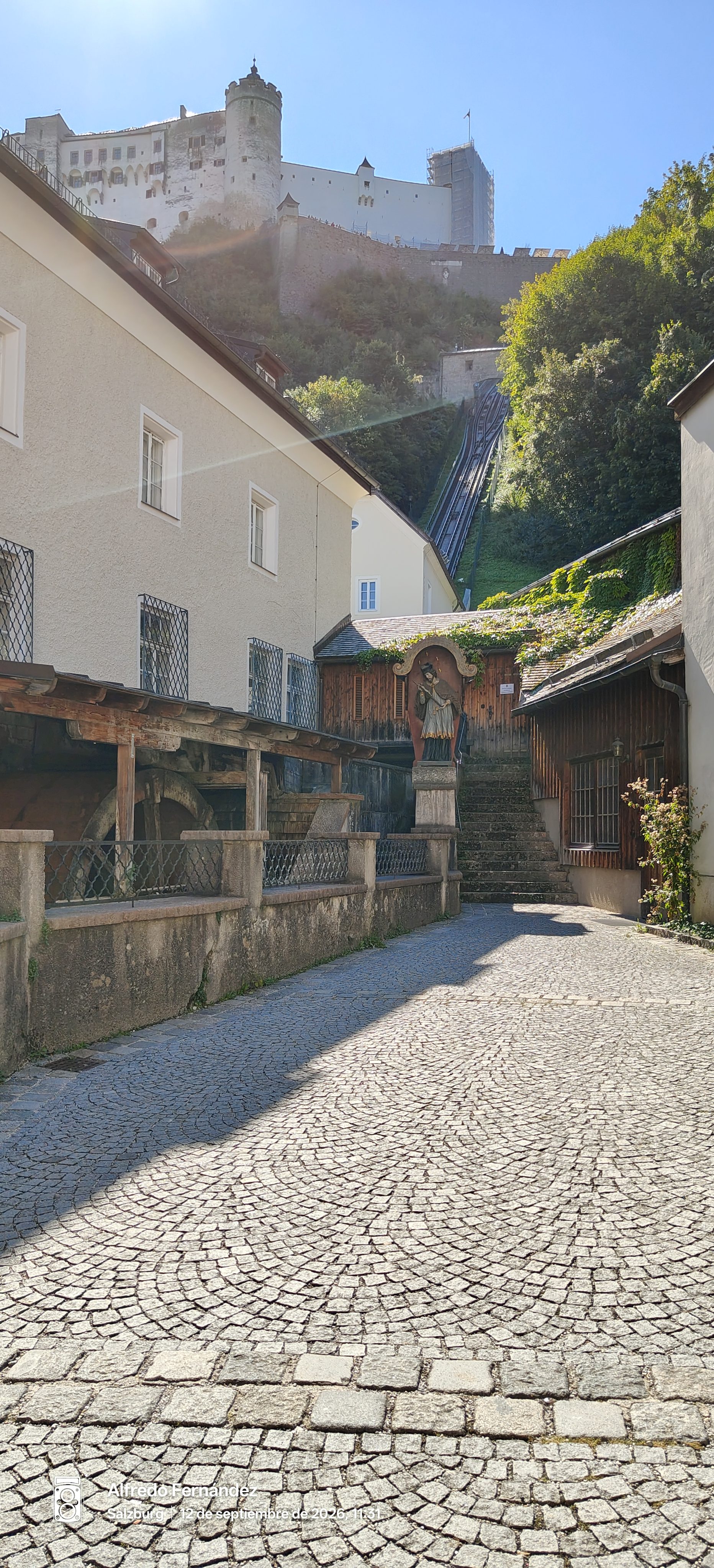 Calle adoquinada con vistas a la fortaleza Hohensalzburg en lo alto de la colina.
