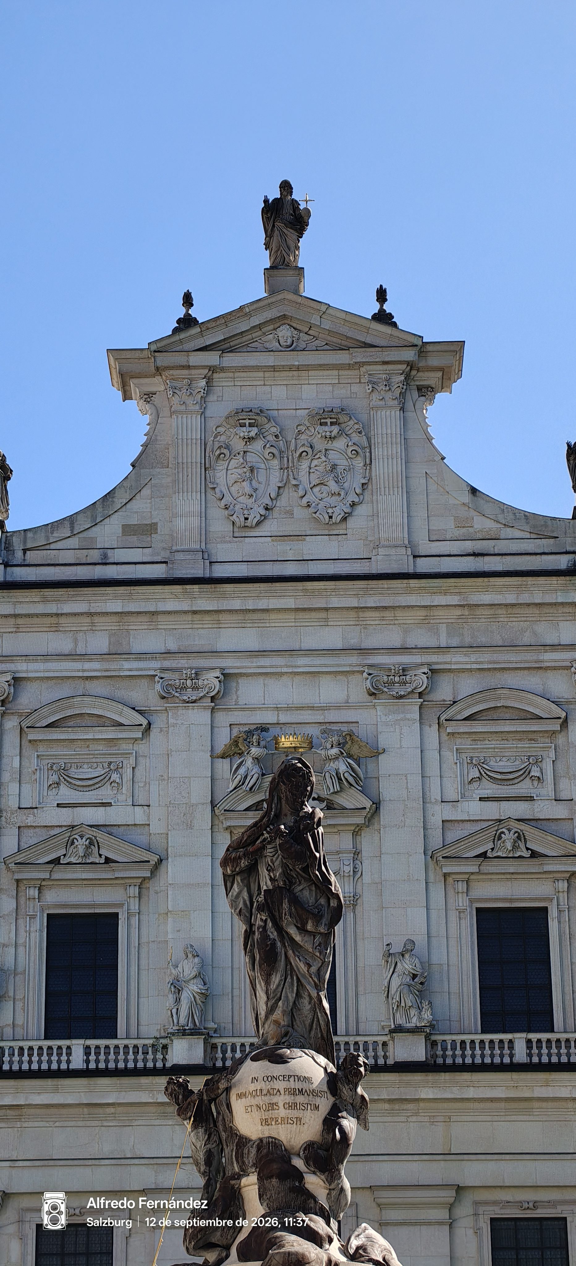 Estatua de la Virgen María frente a la fachada barroca de la catedral de Salzburgo.