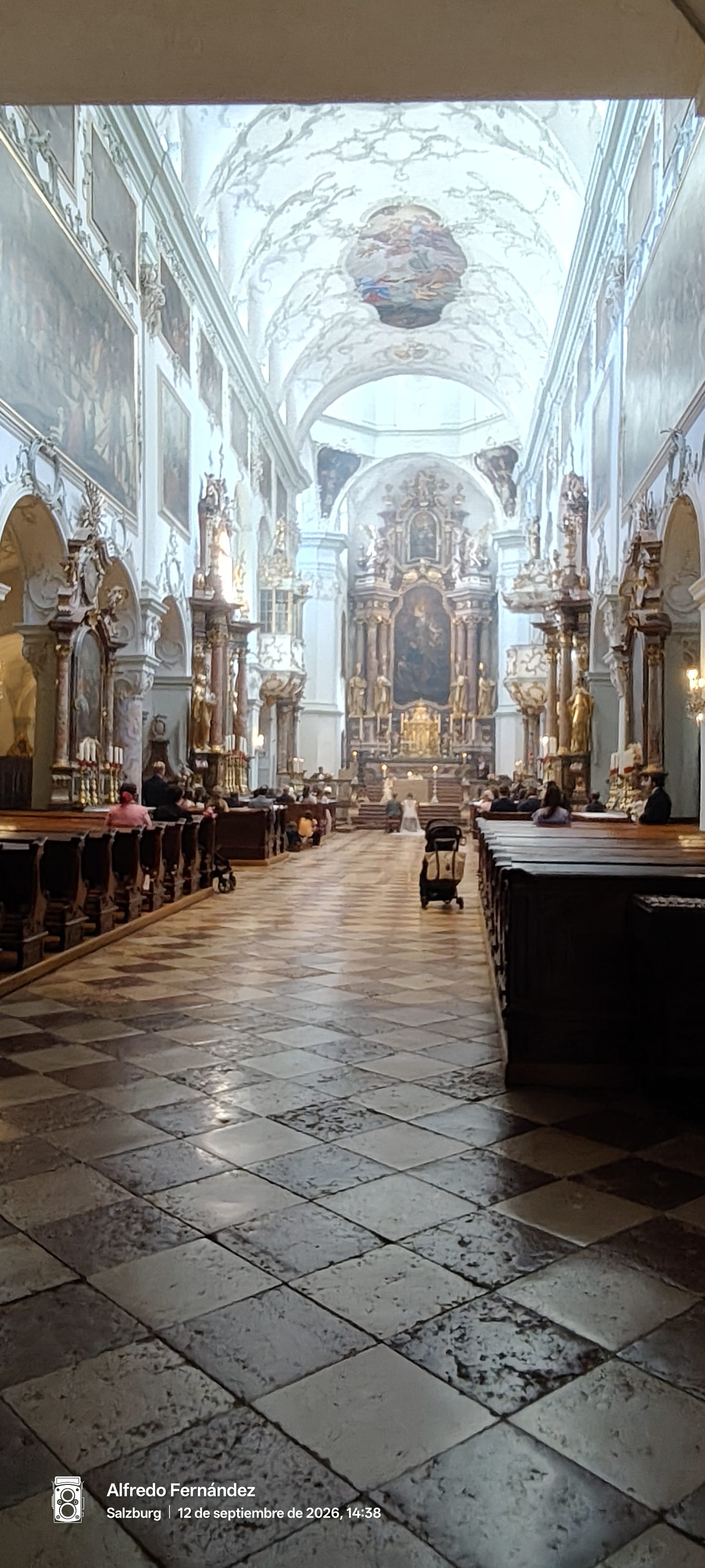 Interior barroco de una iglesia en Salzburgo con suelo ajedrezado y altar ornamental.