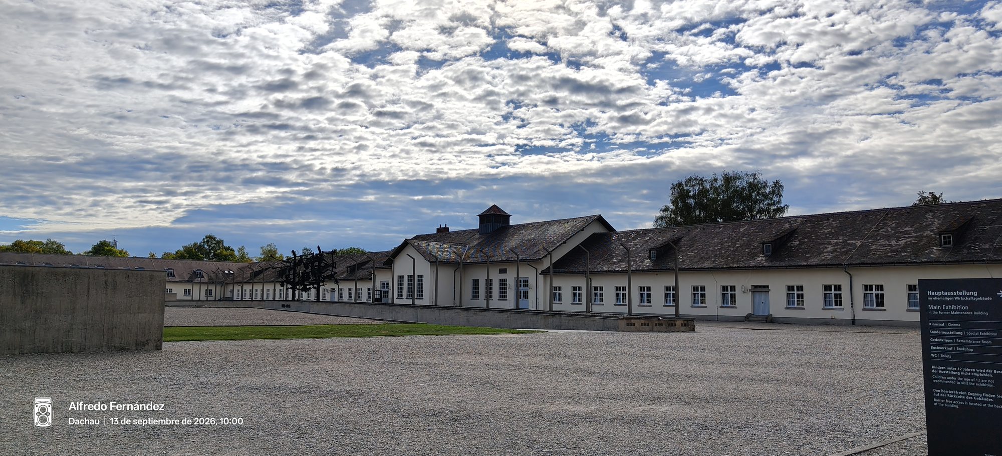 Patio de grava y edificios históricos del memorial de Dachau bajo un cielo nublado.