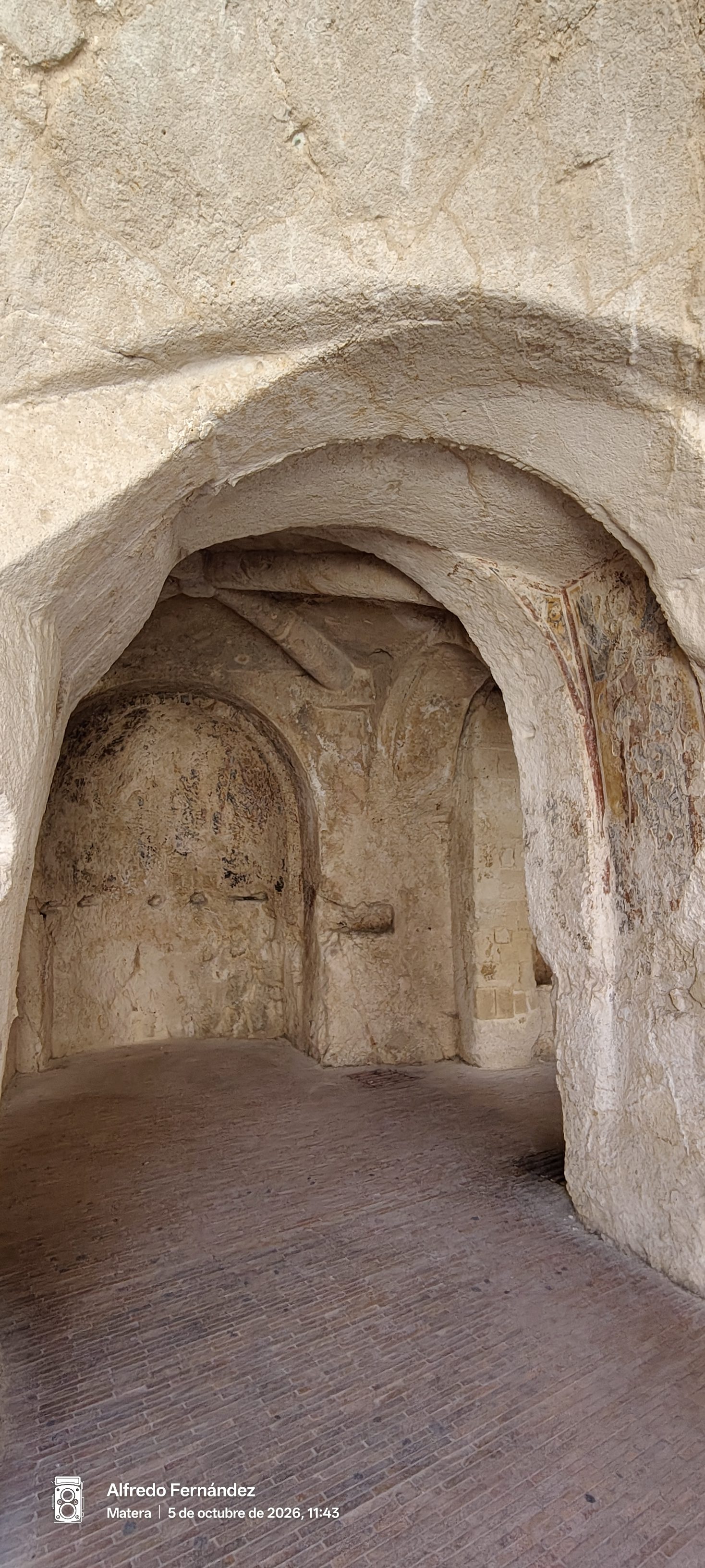 Arcos de piedra y restos de frescos en una iglesia rupestre excavada en roca.