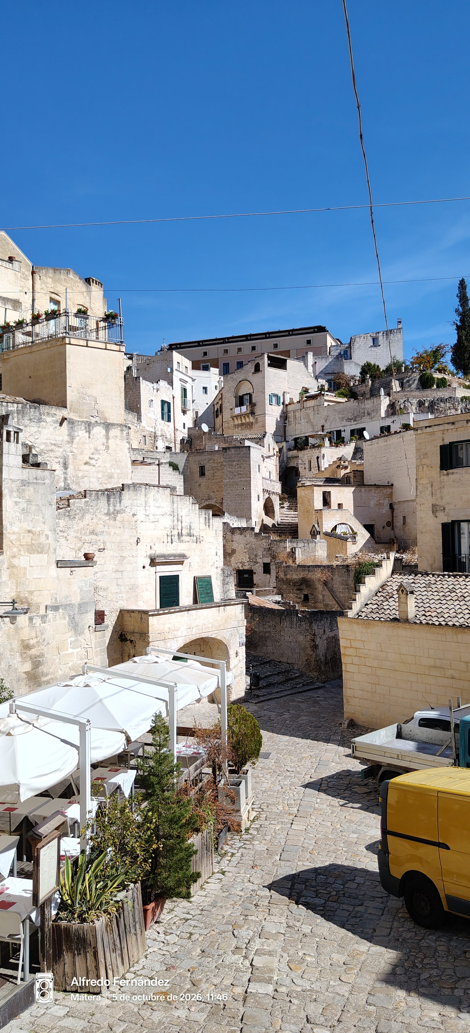 Edificios históricos de piedra caliza y calle empedrada en Matera bajo cielo despejado.