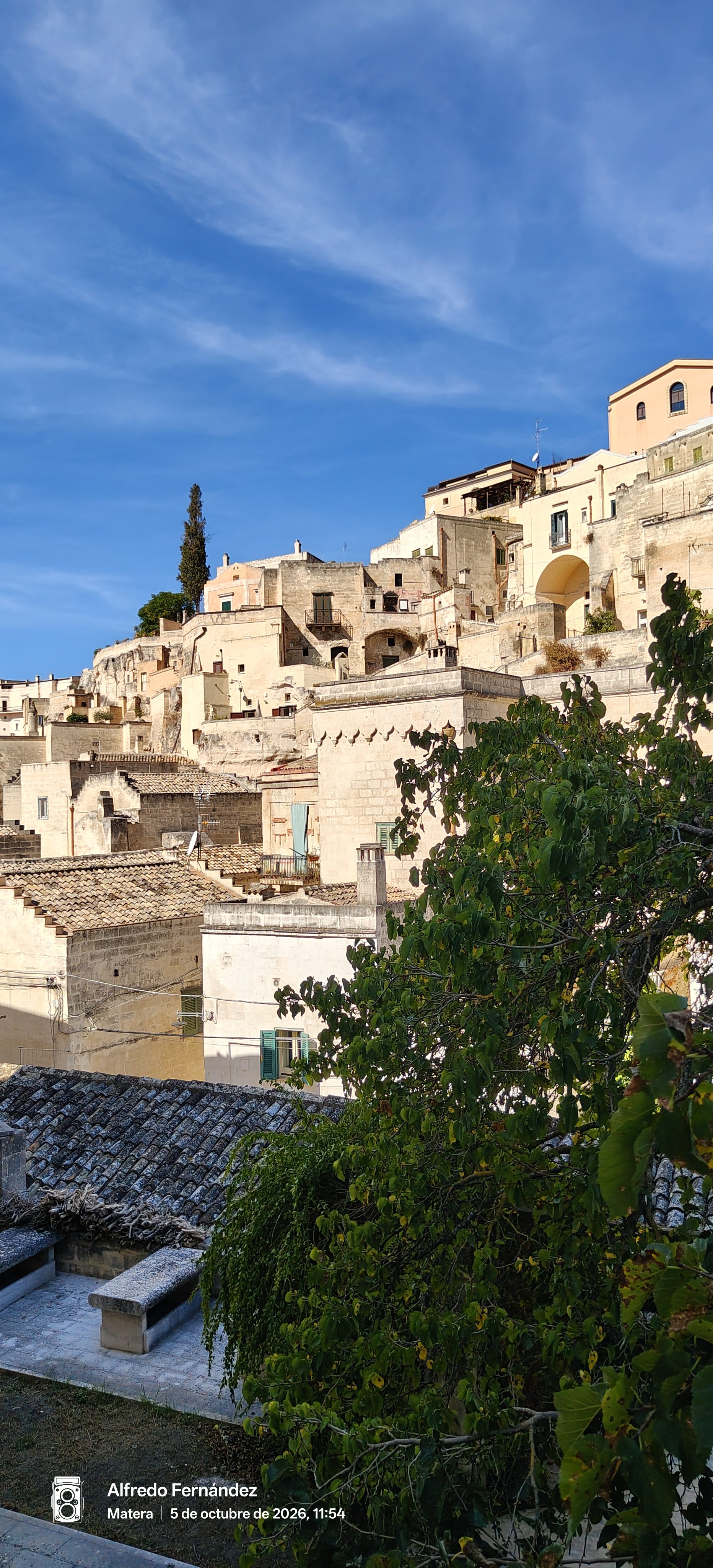 Casas de piedra tradicionales y tejados escalonados en Matera bajo un cielo azul luminoso.