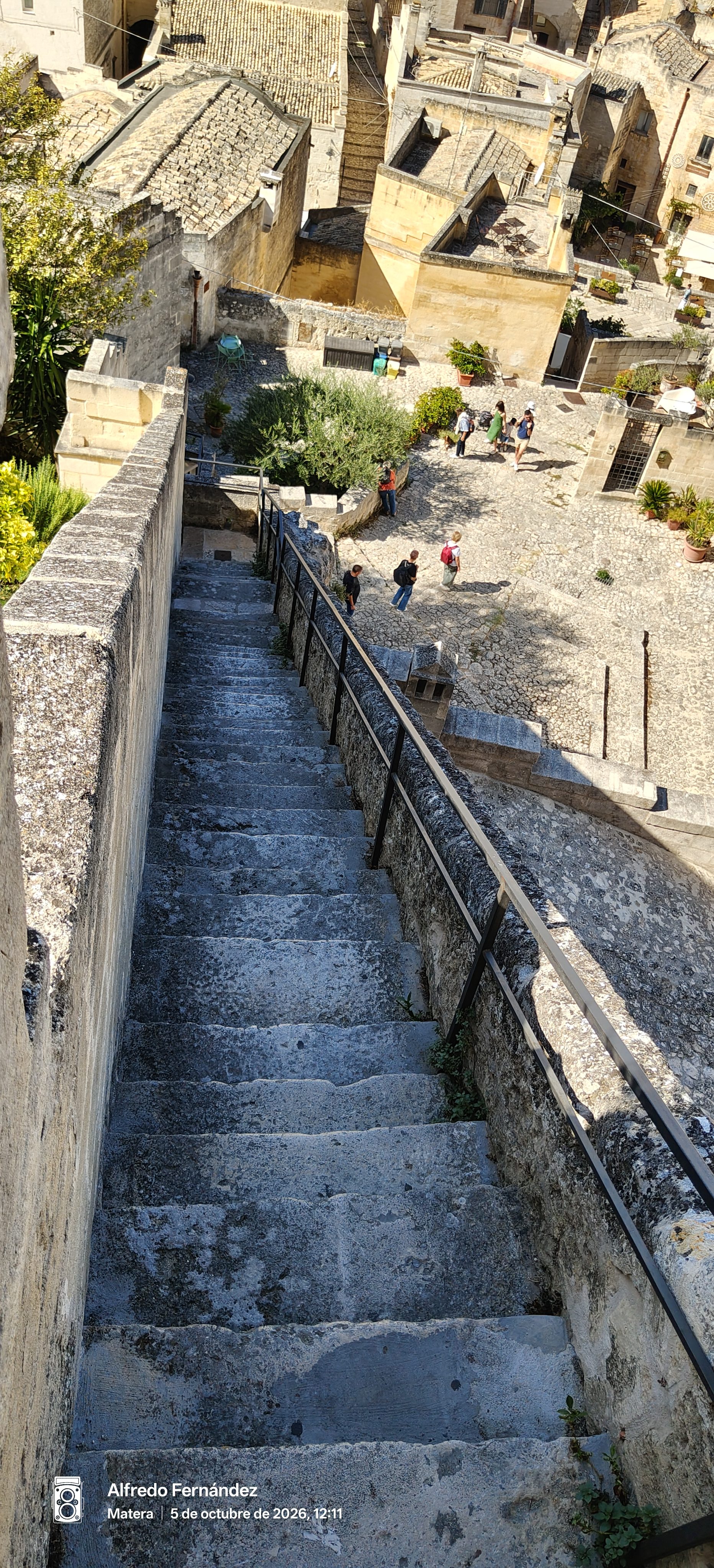 Escalera empinada de piedra que desciende hacia una pequeña plaza histórica en Matera.