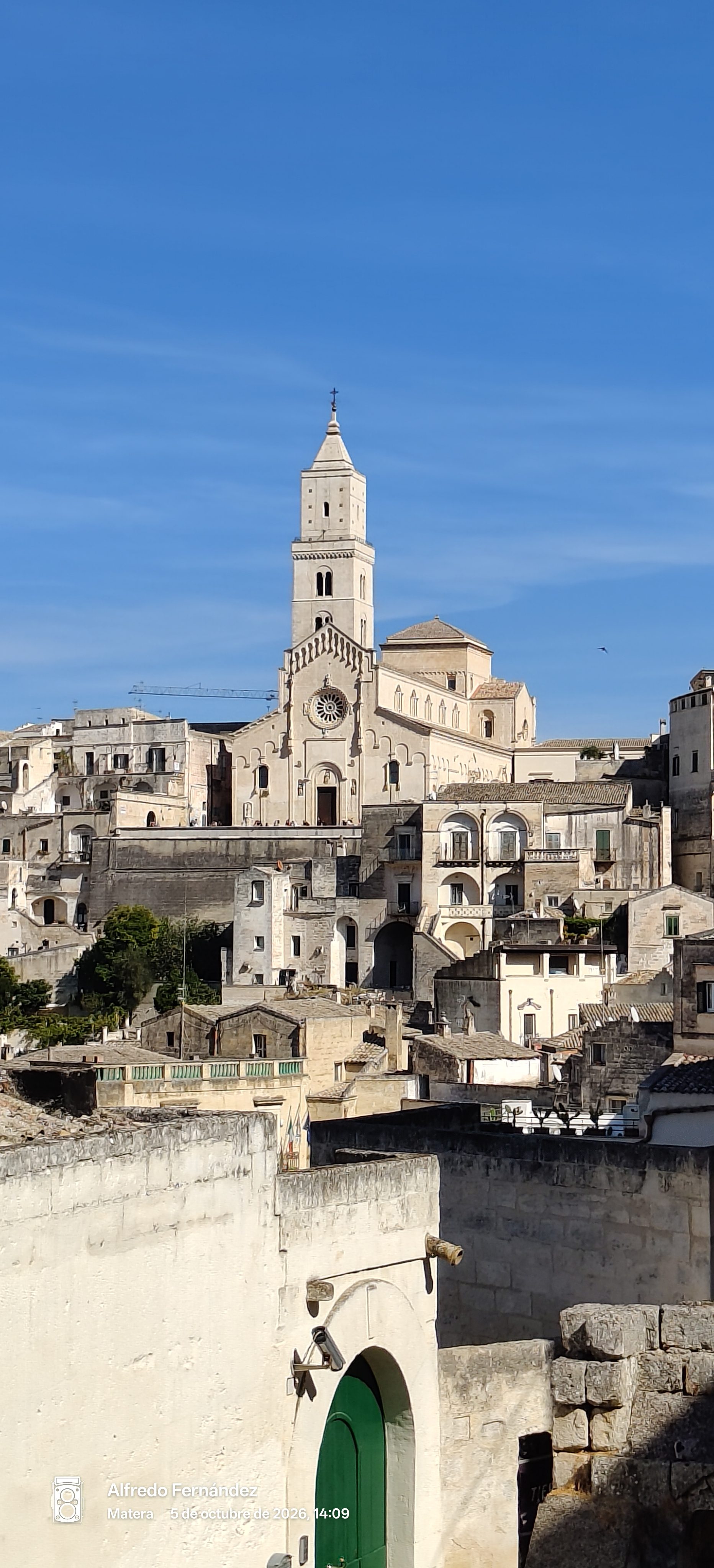 Catedral de Matera alzándose sobre las construcciones de piedra bajo un cielo azul despejado.