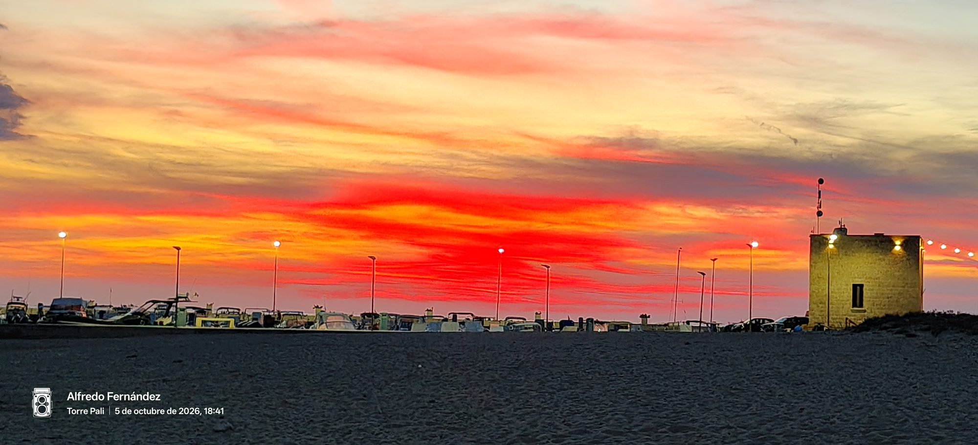 Cielo encendido con tonos rojizos y dorados sobre la playa al atardecer.
