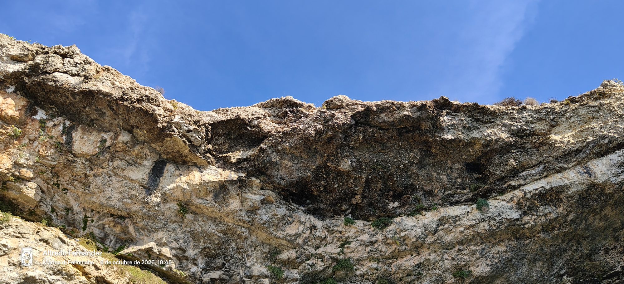Formación rocosa y acantilado escarpado bajo un cielo azul despejado.