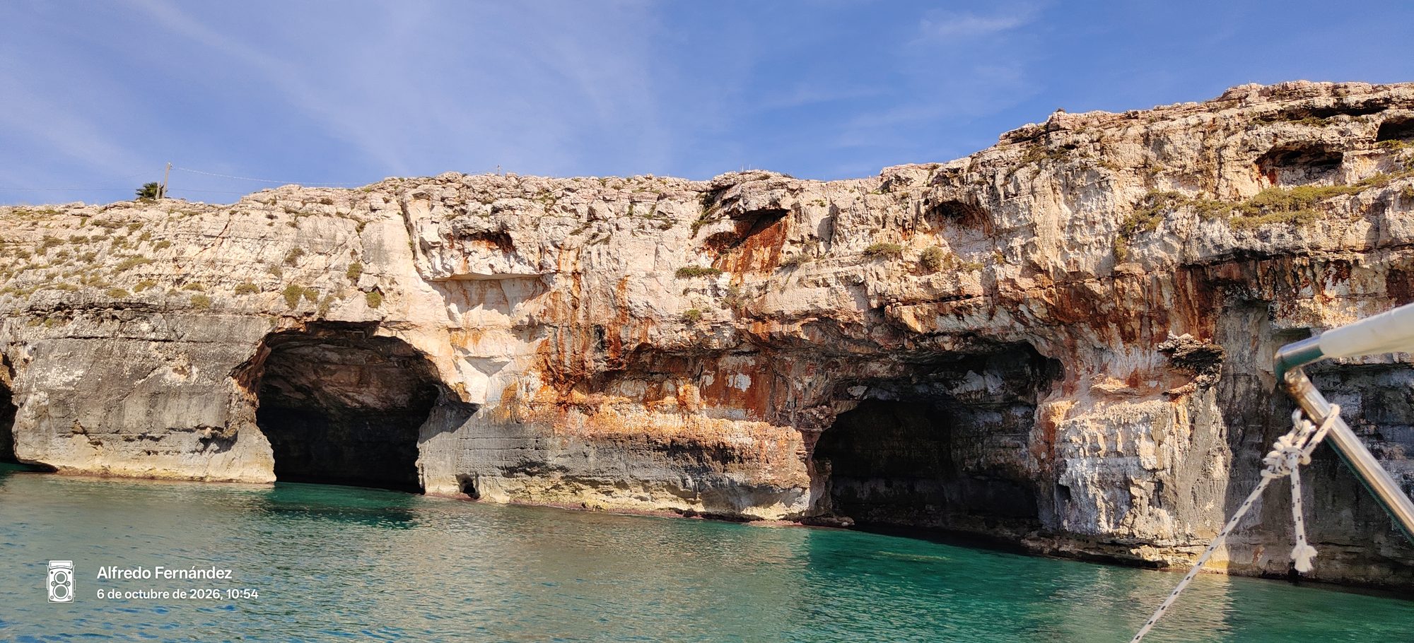 Cuevas marinas y acantilados rocosos sobre aguas turquesas en la costa.