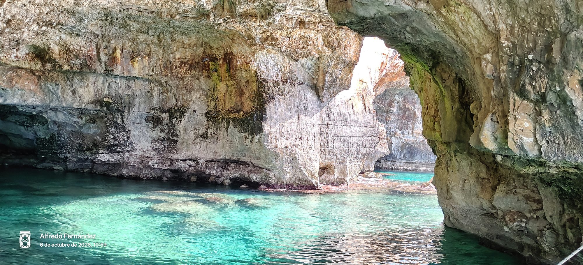 Cueva marina con aguas turquesas cristalinas y arcos de roca natural en la costa.