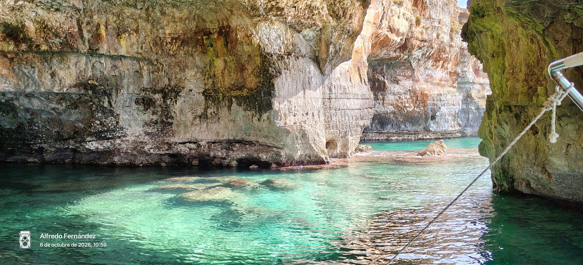 Cueva marina de roca caliza con aguas cristalinas turquesas iluminadas por el sol.