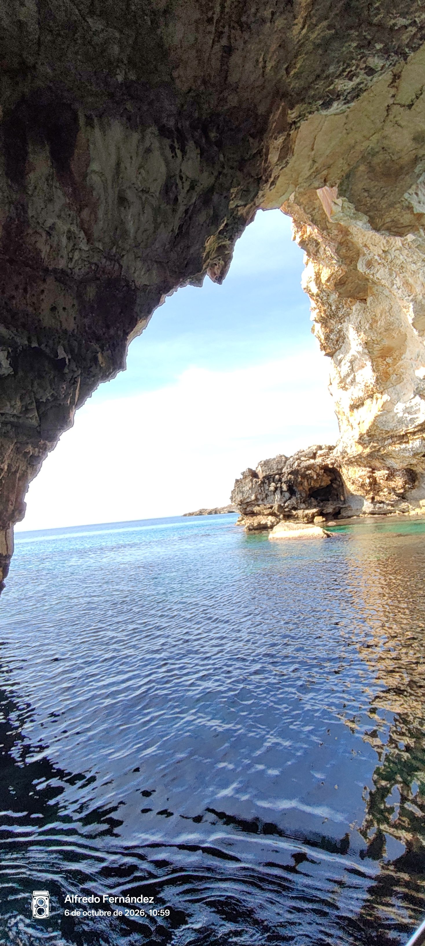 Vista del mar turquesa y acantilados rocosos desde el interior de una cueva marina.