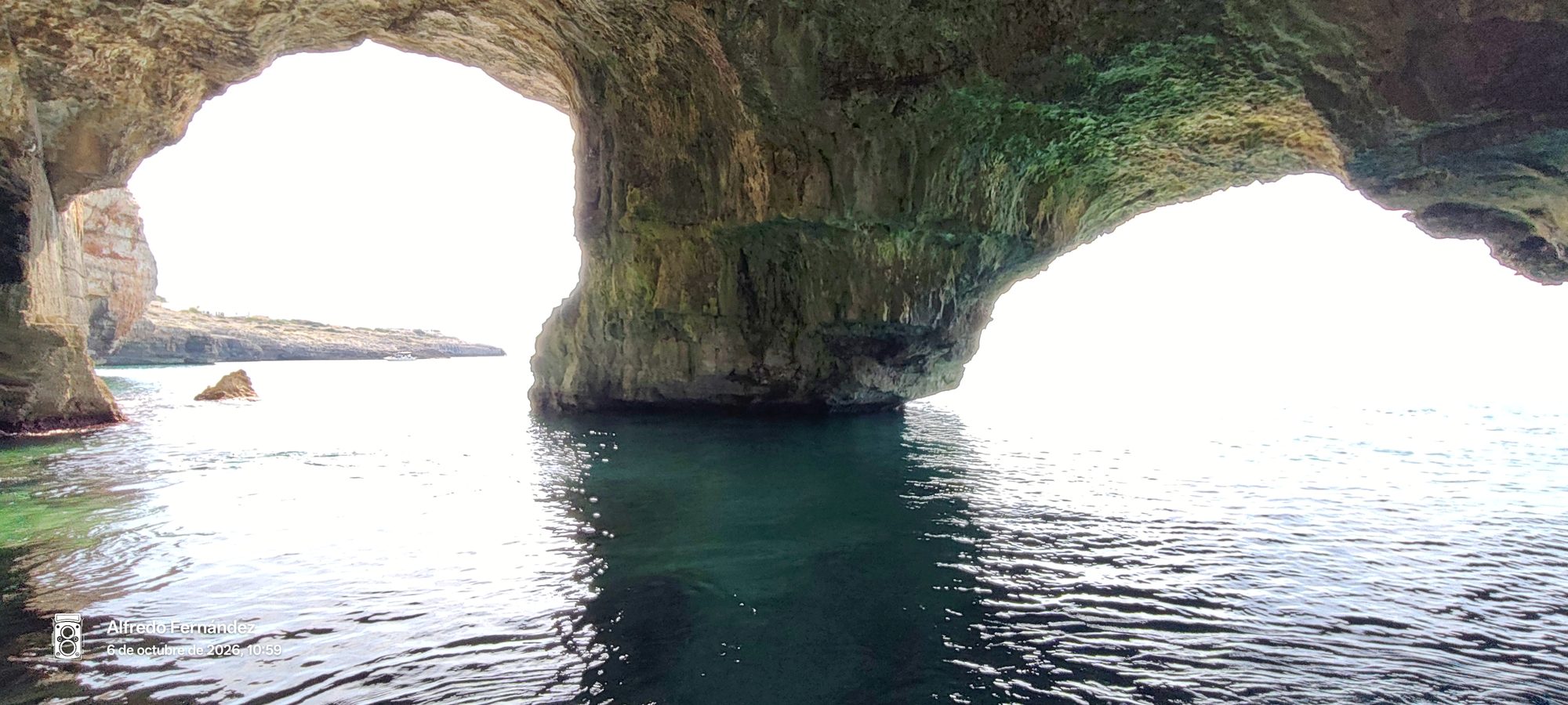 Interior de una cueva marina con arcos de roca natural sobre aguas cristalinas.