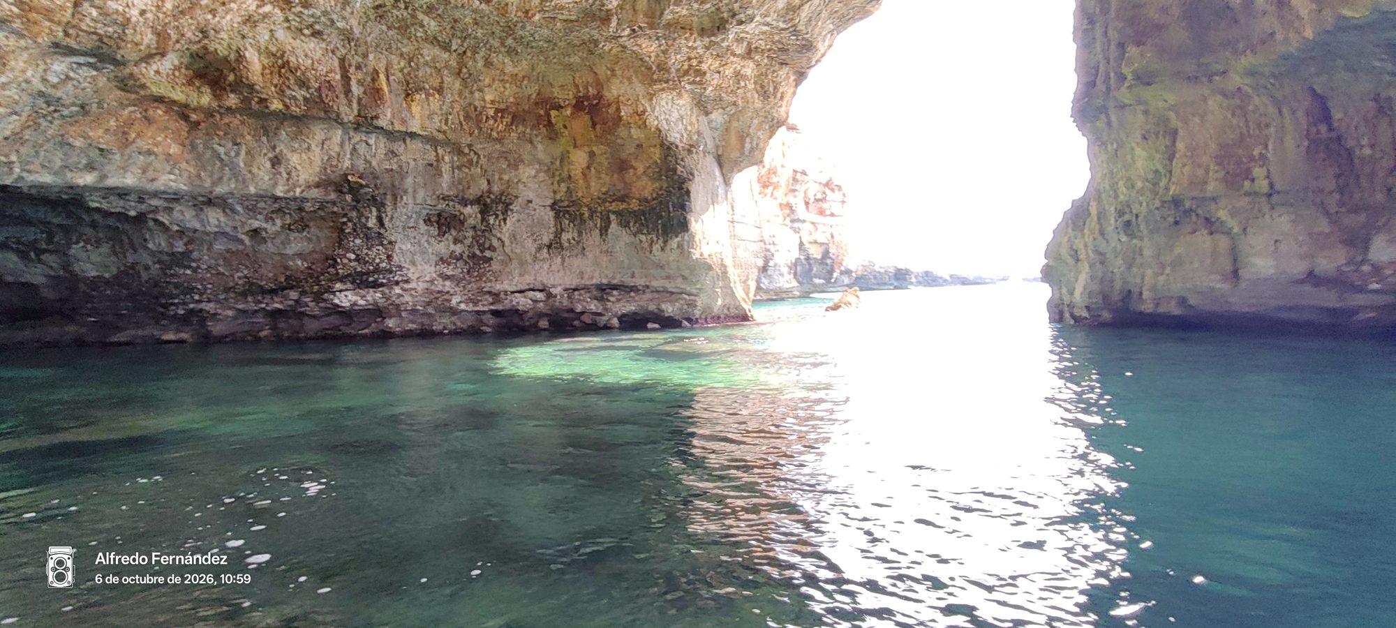 Interior de una cueva marina de roca caliza con aguas cristalinas turquesas.
