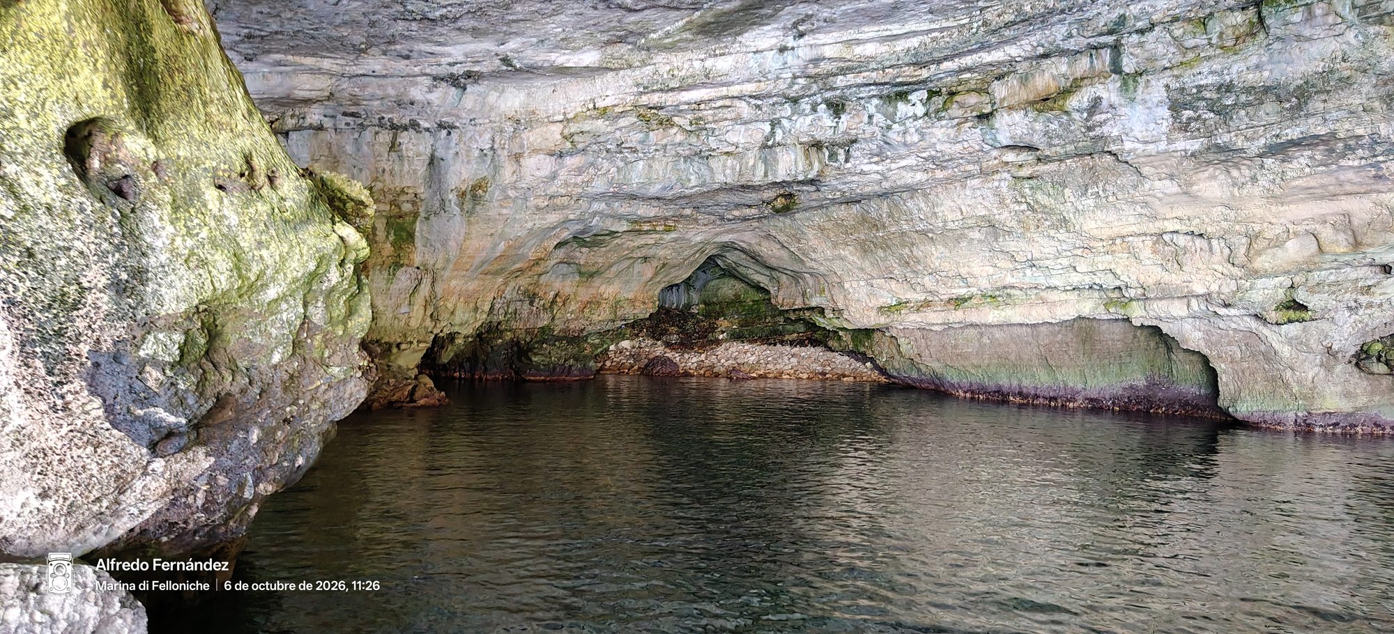 Interior de una gruta marina con paredes de roca caliza y aguas cristalinas.