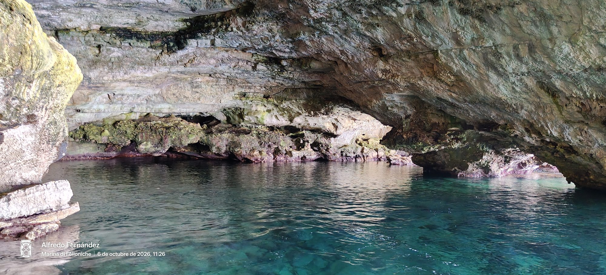 Interior de una cueva marina rocosa sobre aguas cristalinas de tono turquesa.