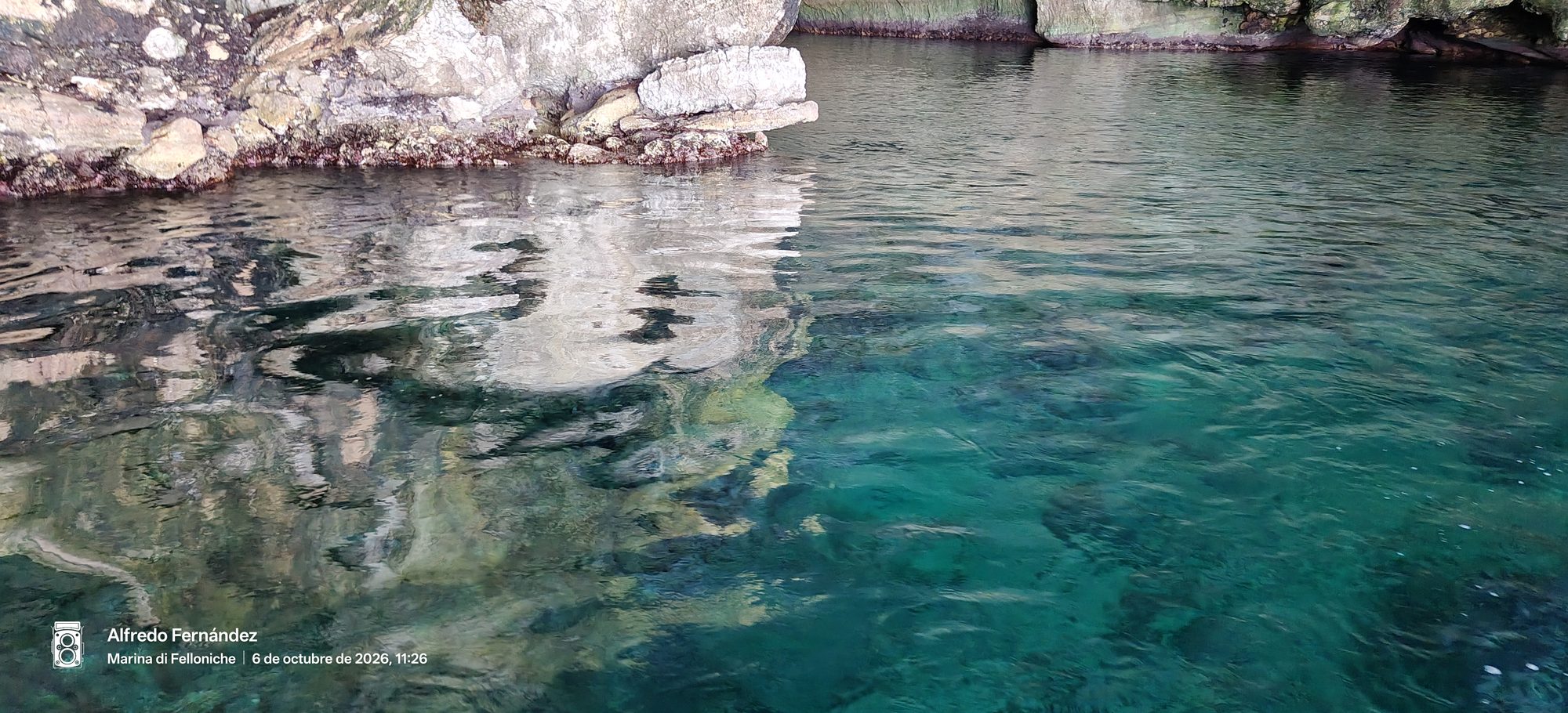 Aguas cristalinas de color turquesa reflejando acantilados rocosos en la costa marina.