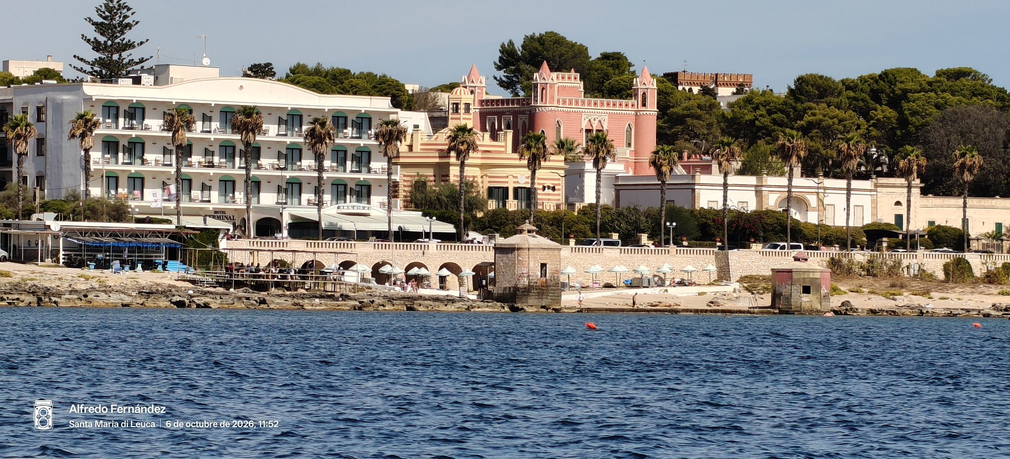Paseo marítimo de Santa Maria di Leuca con villas históricas, palmeras y mar azul.