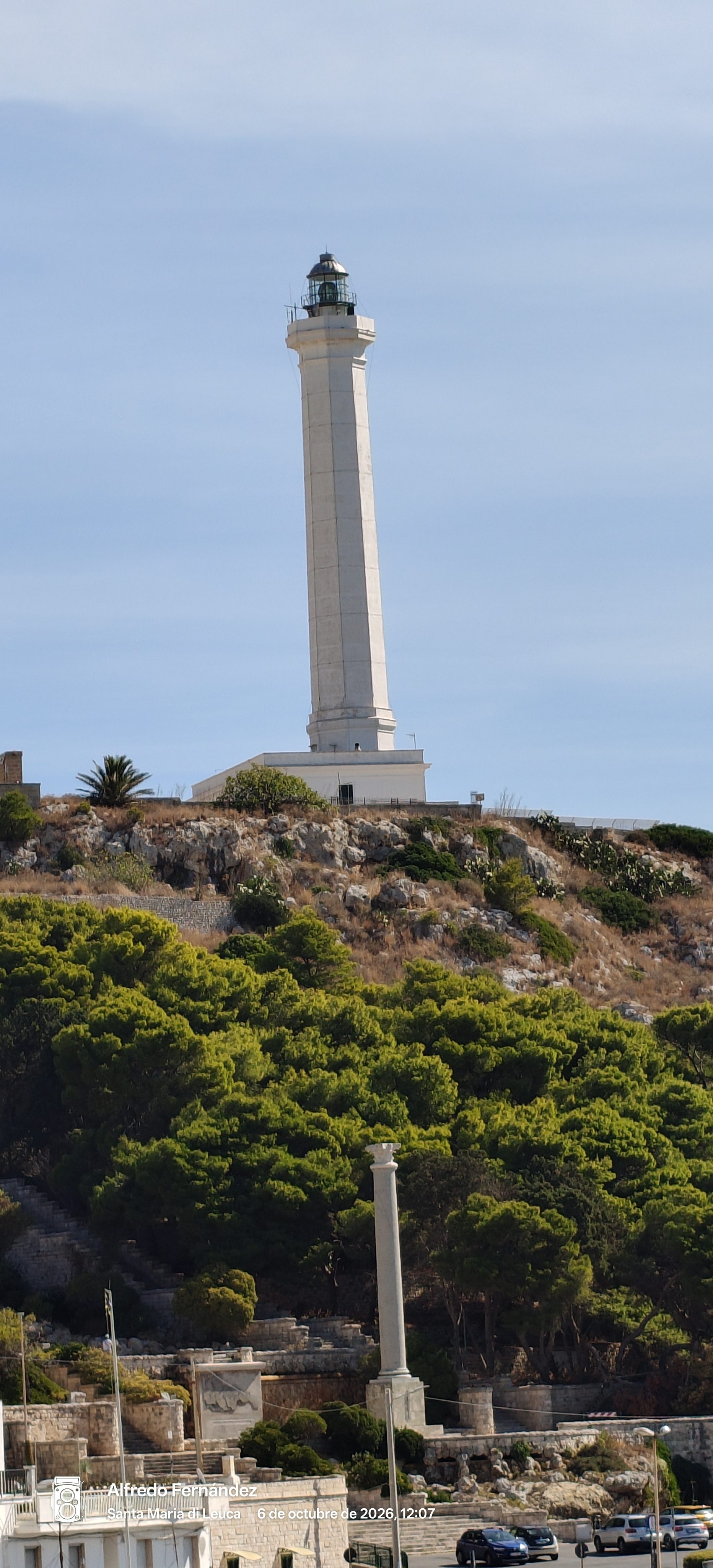 Faro blanco alto sobre una colina rocosa con pinos en Santa Maria di Leuca.