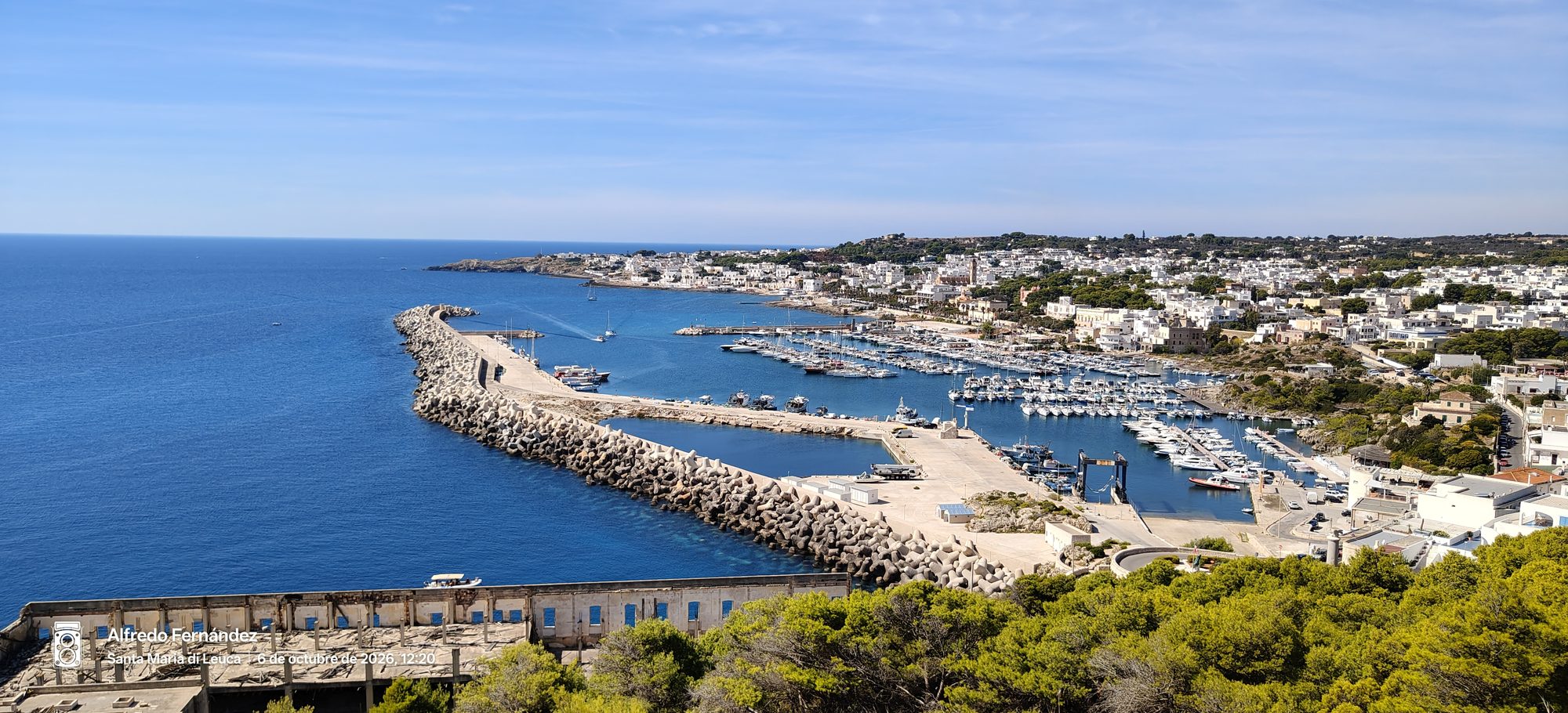 Vista panorámica del puerto deportivo y rompeolas con barcos en la costa de aguas azules.