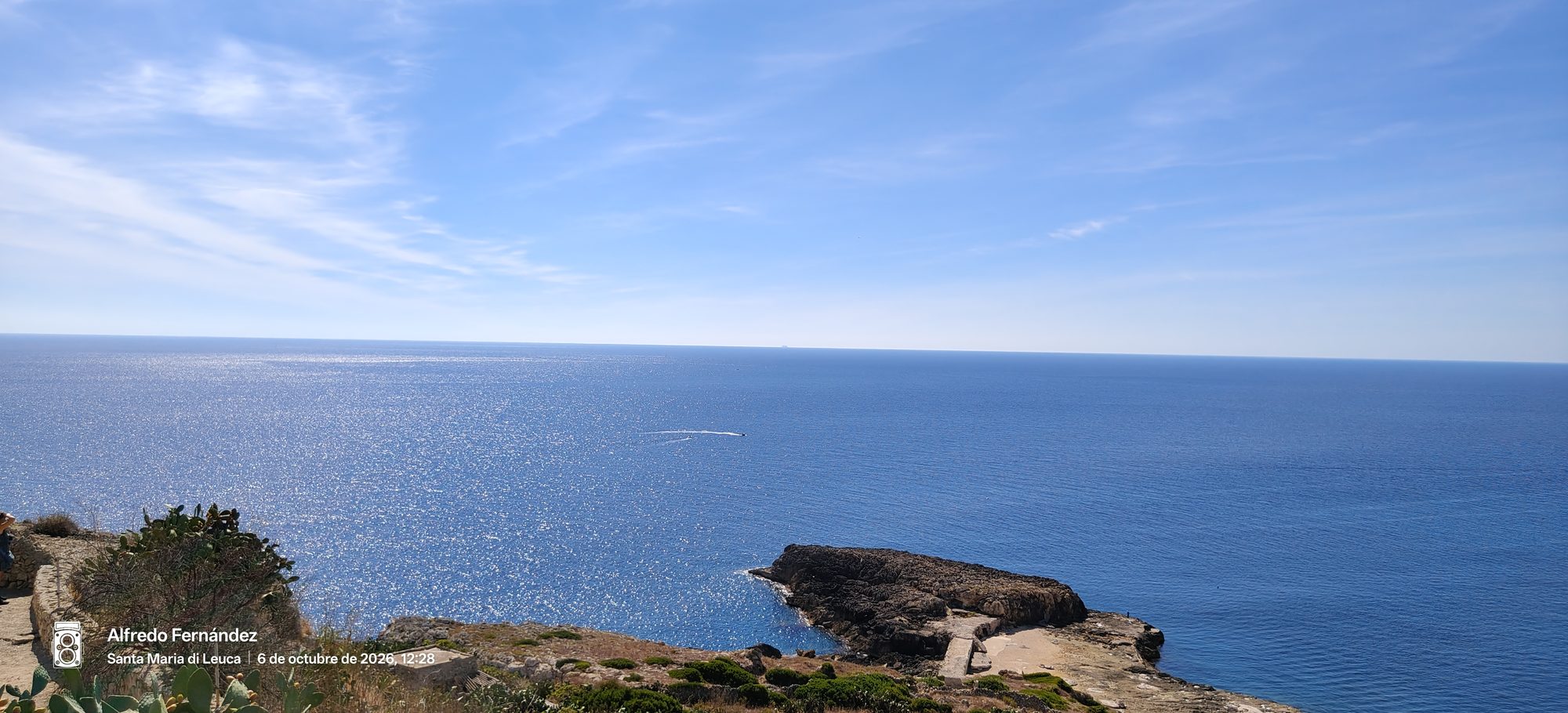 Acantilados rocosos frente al inmenso mar azul brillante bajo un cielo despejado.