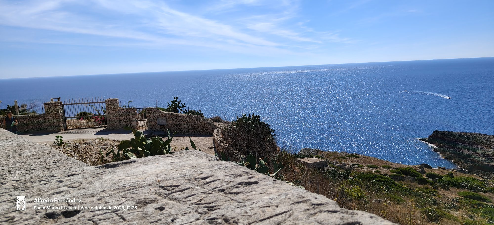 Mirador de piedra con cactus frente al mar azul brillante bajo un cielo despejado.
