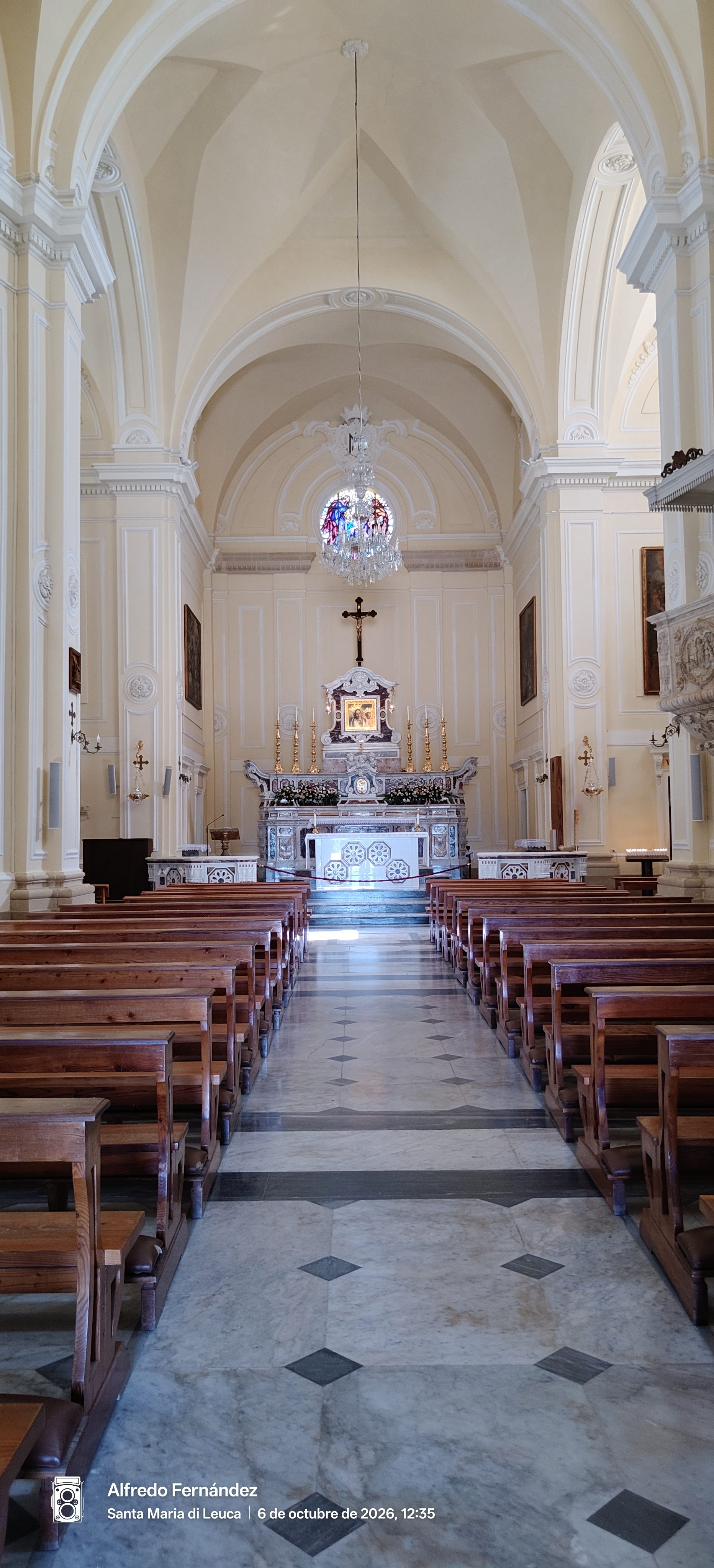 Nave interior de una luminosa iglesia con bancos de madera hacia el altar mayor