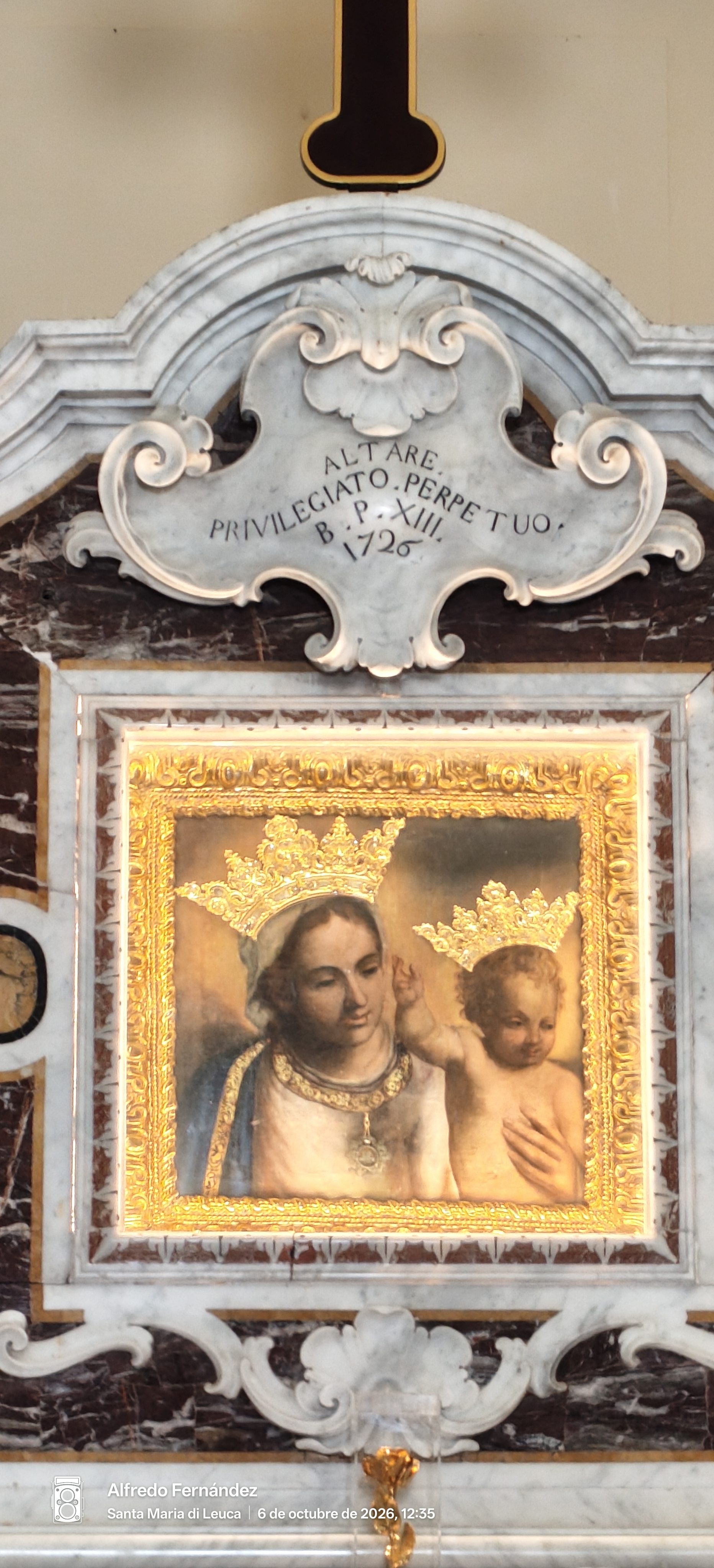 Pintura de la Virgen María con el Niño Jesús coronados en un altar de mármol.