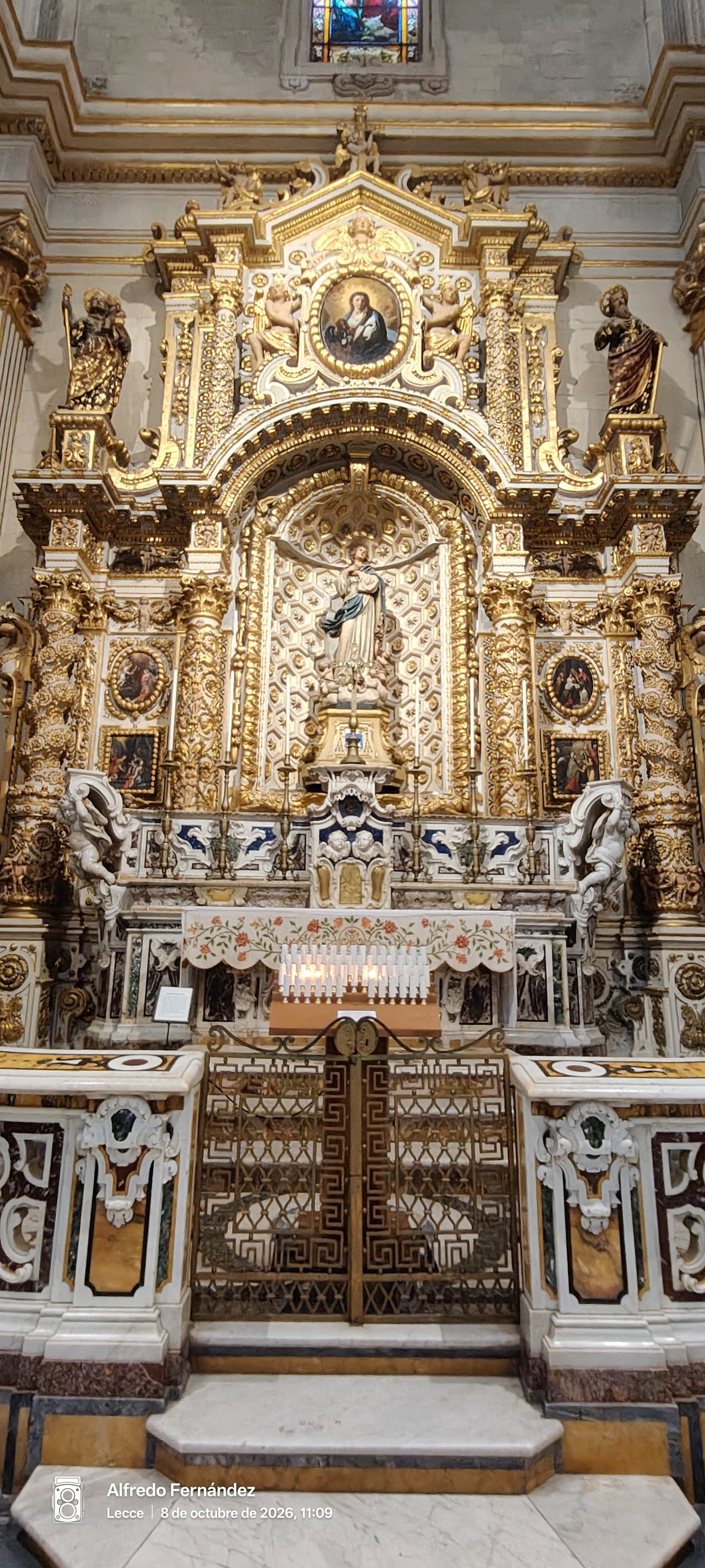 Altar barroco dorado con esculturas religiosas y cancela de mármol en una iglesia.