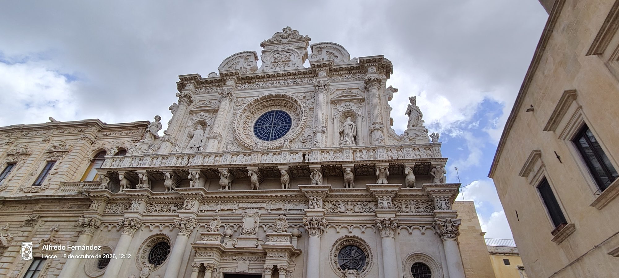 Fachada barroca de la Basílica de Santa Cruz con intrincadas esculturas de piedra y rosetón.