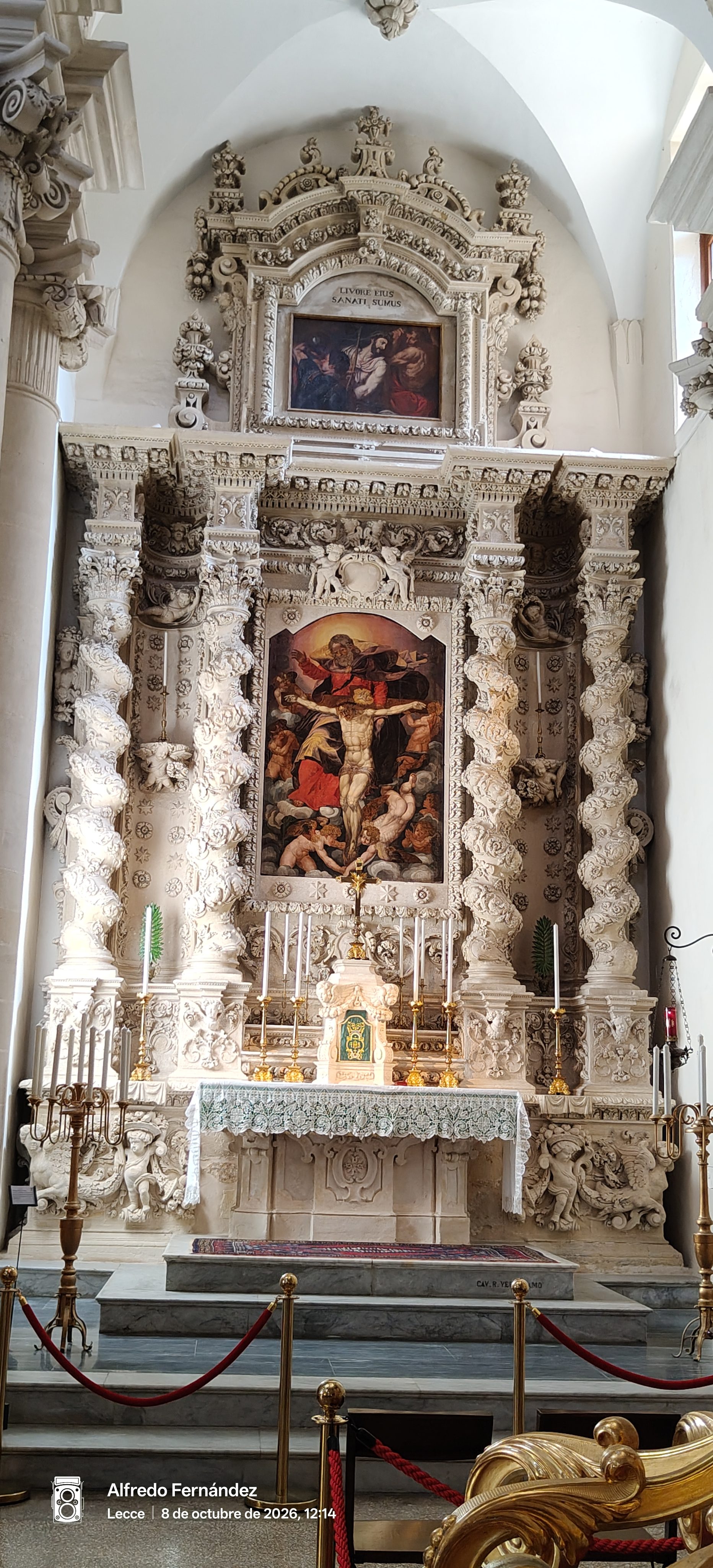 Altar barroco de piedra tallada con columnas salomónicas y pinturas religiosas en una iglesia.