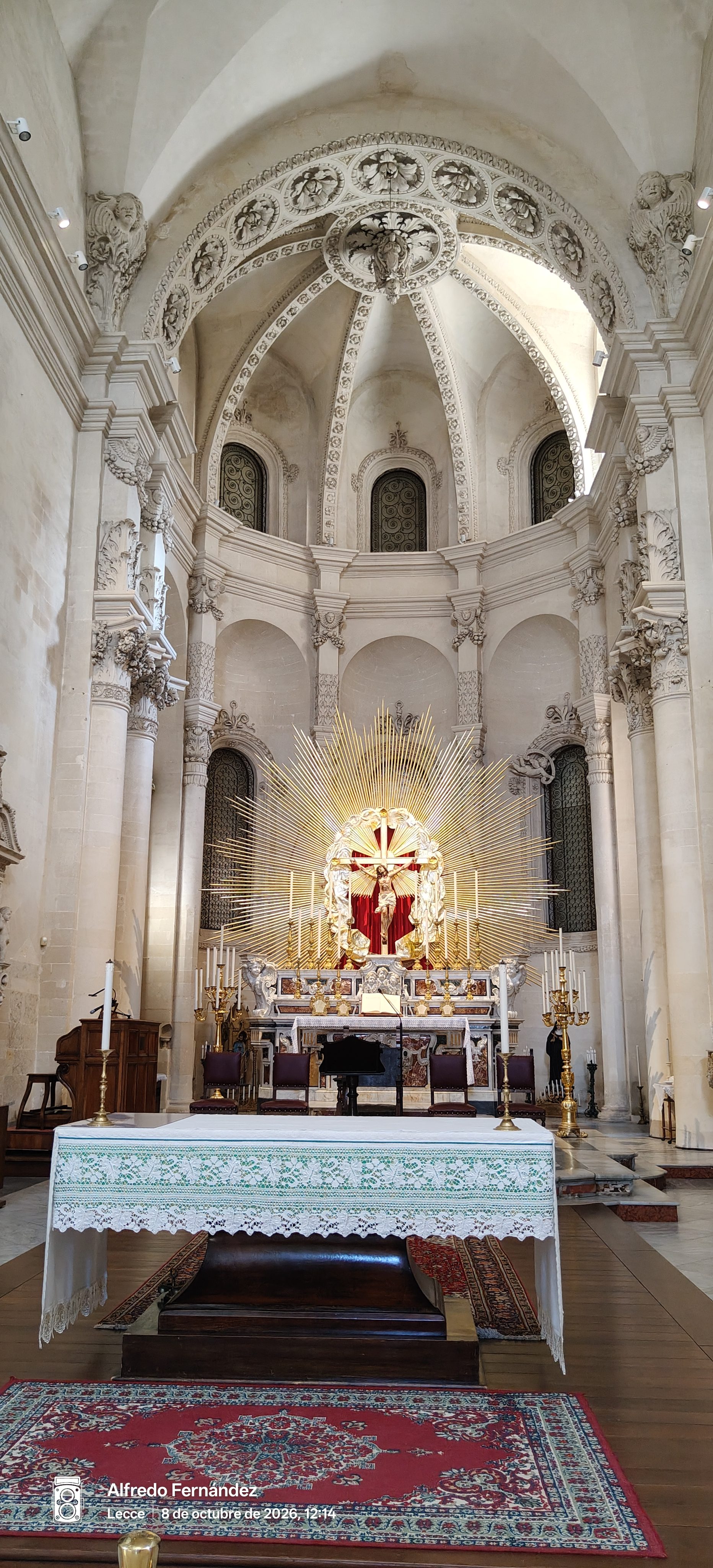 Altar mayor barroco con crucifijo dorado resplandeciente en el interior de una iglesia.