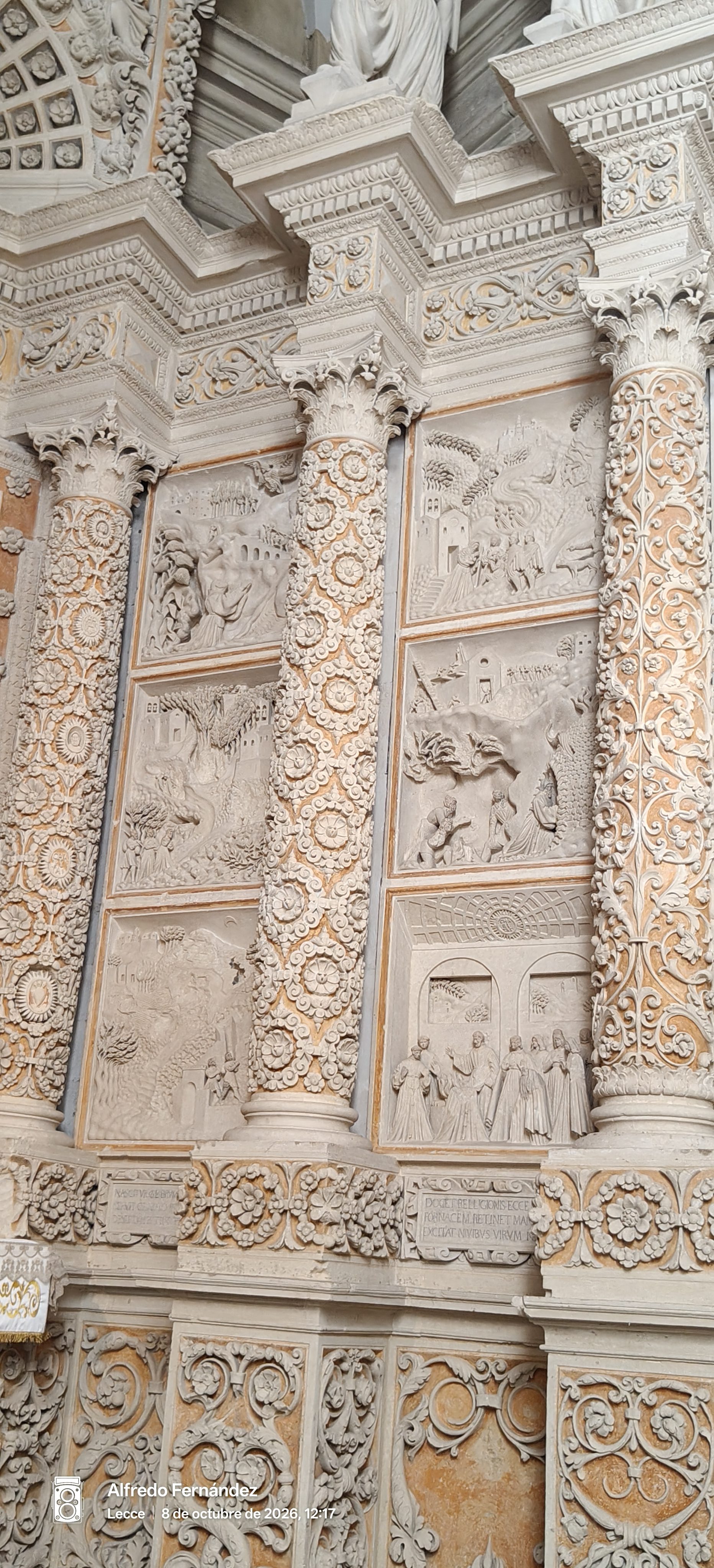 Relieves barrocos de piedra tallada y columnas ornamentadas con motivos florales en una iglesia.