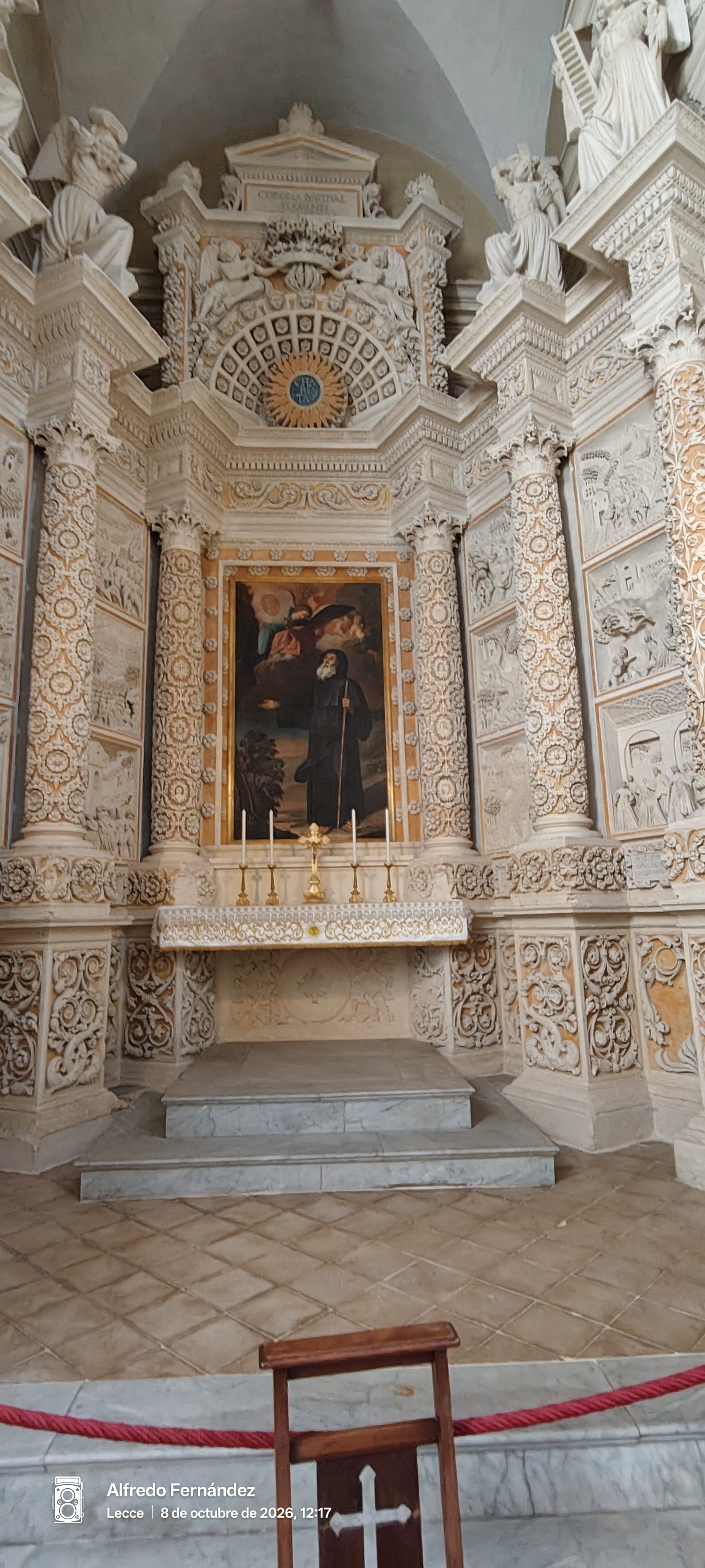Altar de piedra tallada de estilo barroco con columnas esculpidas y una pintura central.