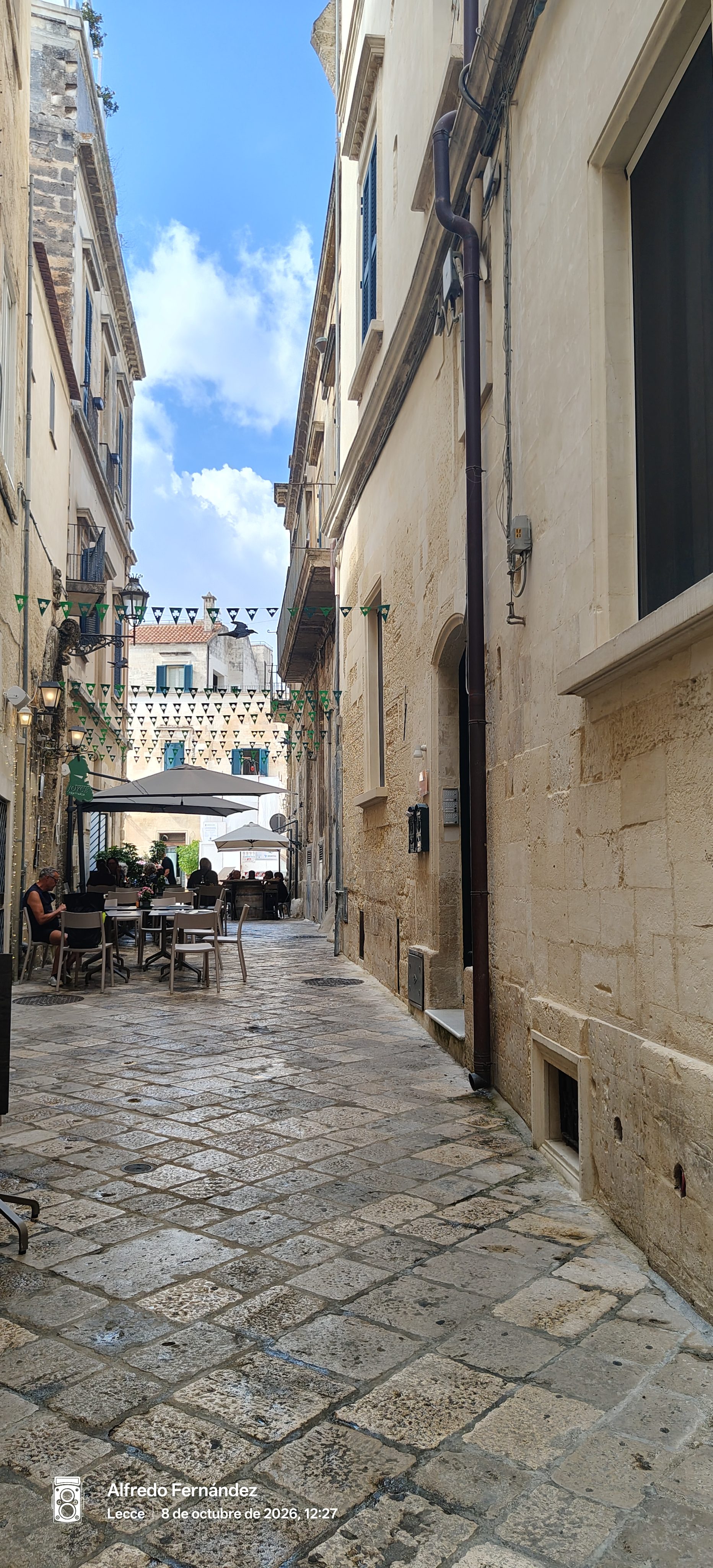 Callejón empedrado con edificios de piedra caliza y terrazas al aire libre en Lecce.