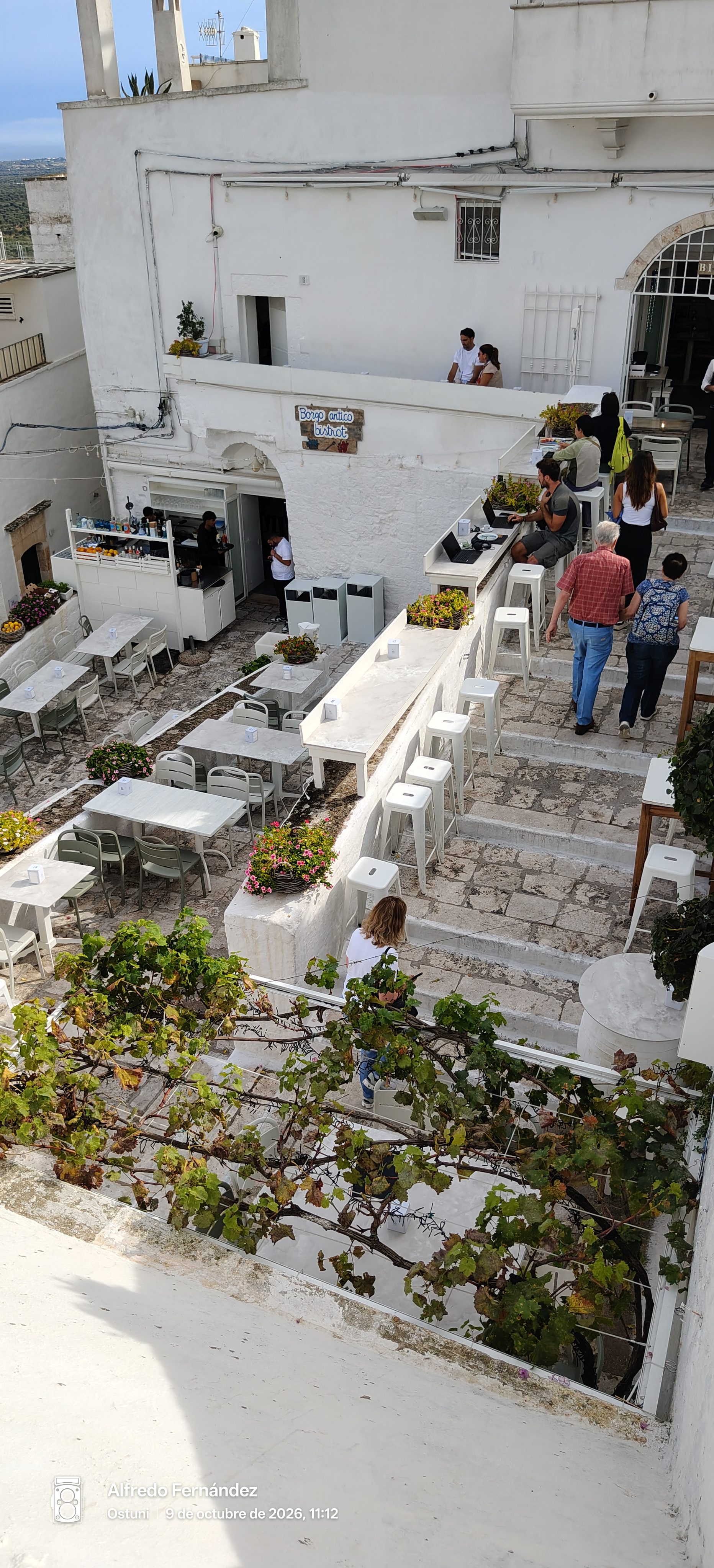 Terraza escalonada de un bistrot entre edificios blancos de piedra en Ostuni.